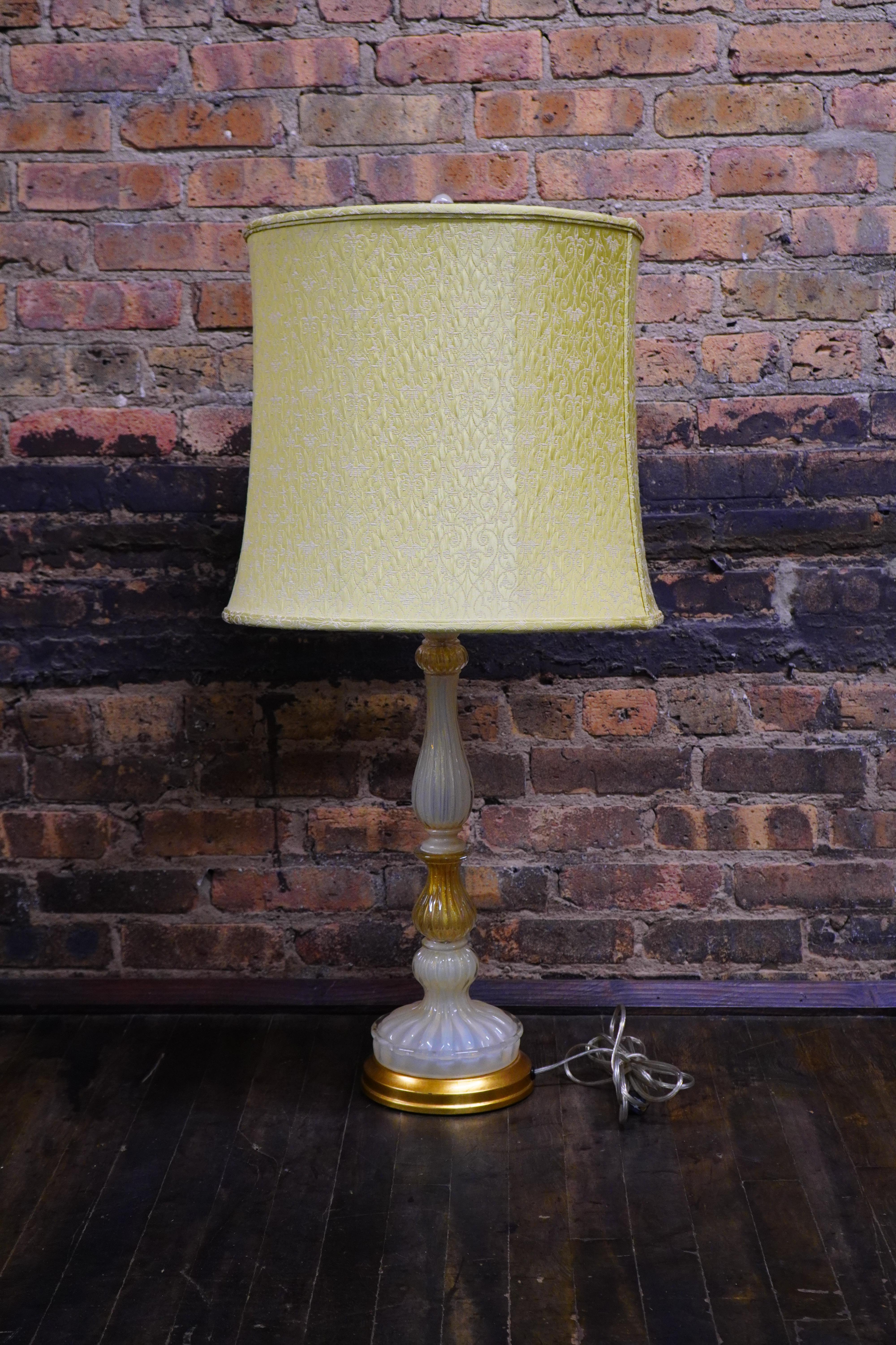 A stunning and stately vintage Murano glass table lamp that had a lovely scalloped, fluted design.  

The lamp features abundant and luxurious gold flecks (some inside ivory colored glass and some in clear glass).  It has a very rich and regal body