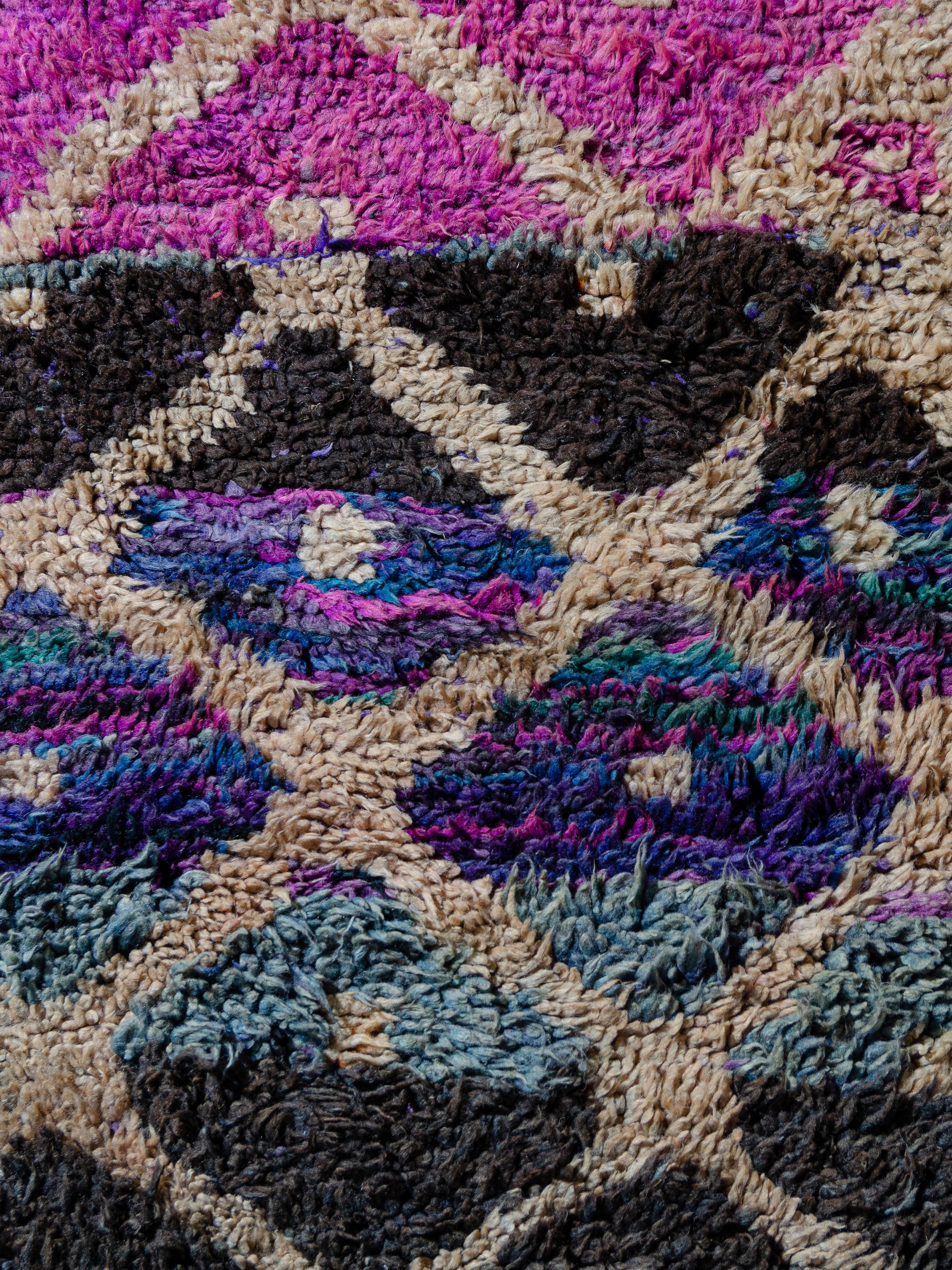 Unapologetic and unafraid of color, this vintage Boujad features an ecru lozenge network overlaying a field of vibrant fuchsia, violet, teal, turquoise, and dark brown. The neutral layer has a fluid quality, gradating in density across the
