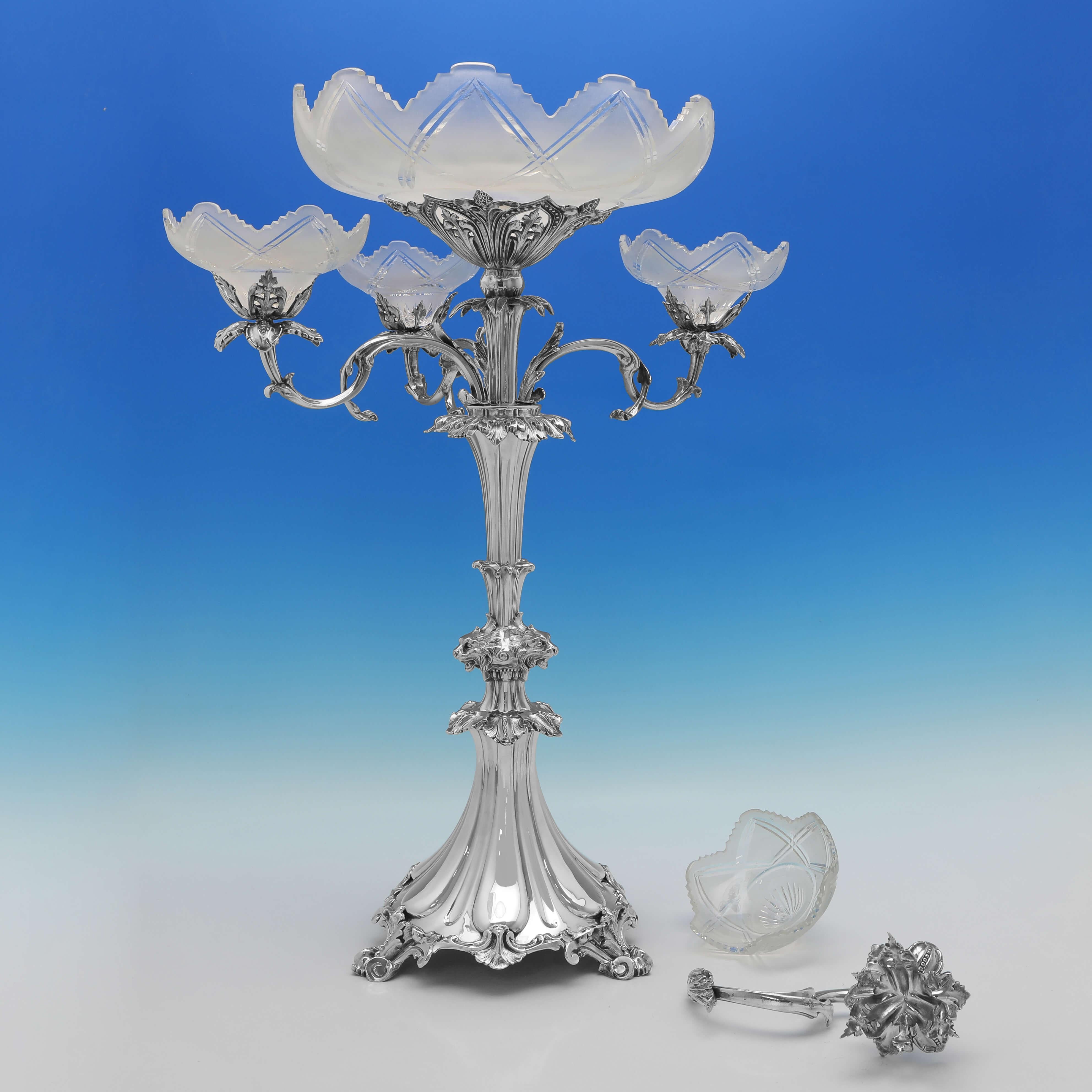 Made circa 1880, this striking and large, Antique Silver Plated Centrepiece, features ornate decoration on the feet and the arms, a central large glass dish, and four smaller side glass dishes. The epergne measures 27.5