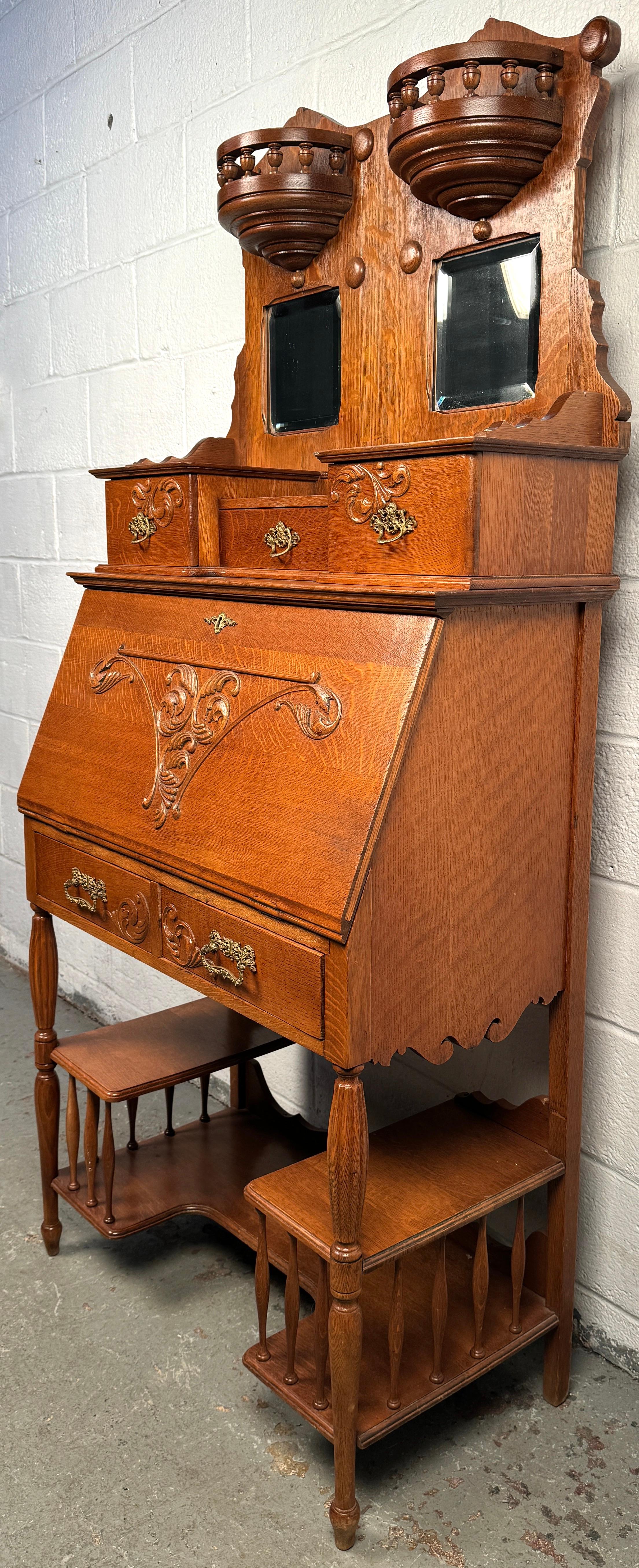 Elevate your interior with the timeless elegance of this Victorian antique slant front desk, crafted in richly grained golden oak and featuring a rare built-in étagère — the perfect marriage of beauty and functionality.

Dating to the late 19th
