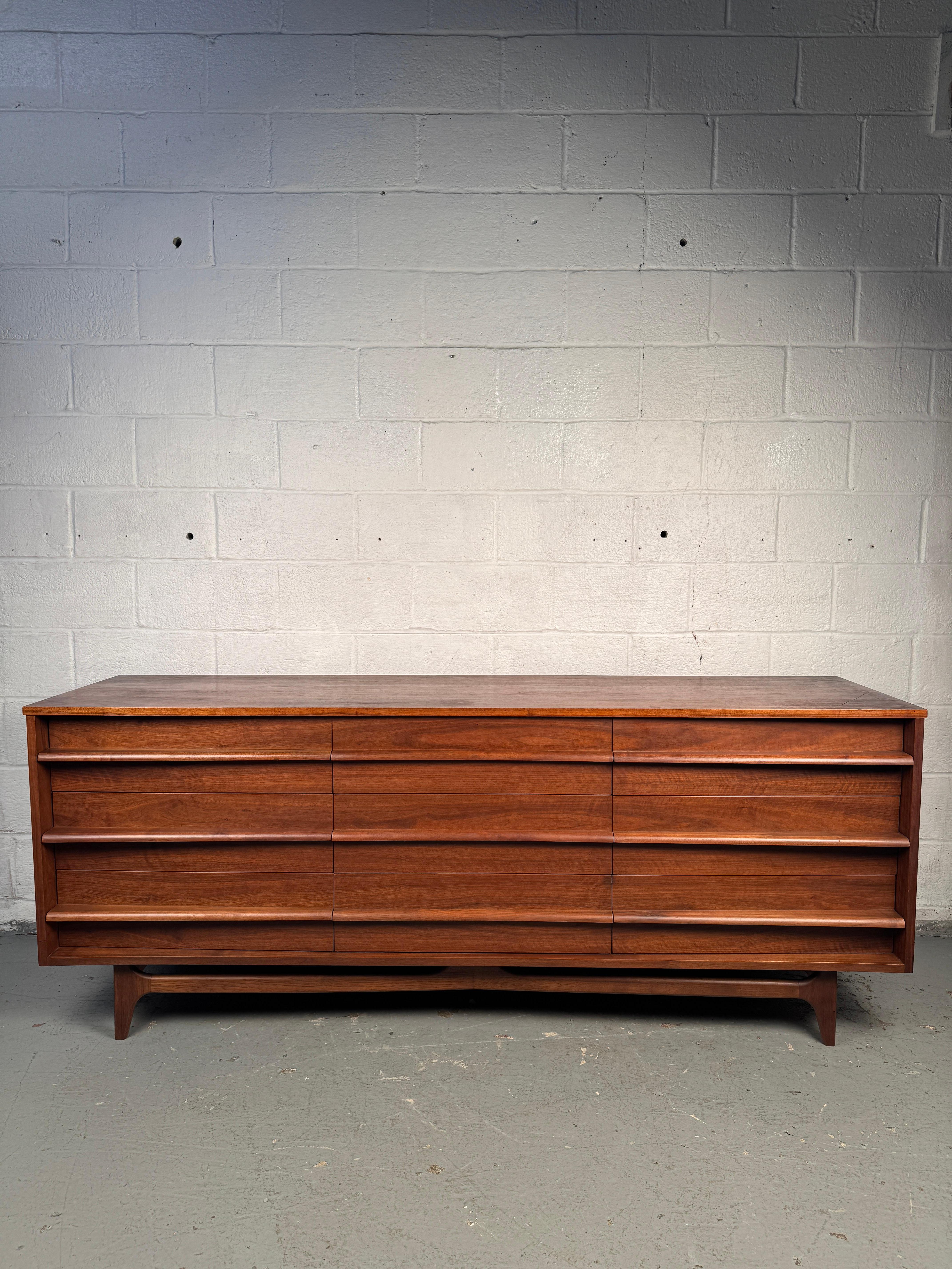 Elegant mid-century dresser by Young Manufacturing, crafted in richly grained walnut. The case features a distinctive curved front with sculptural drawer pulls, combining sleek design with generous storage. A striking and inspiring example of