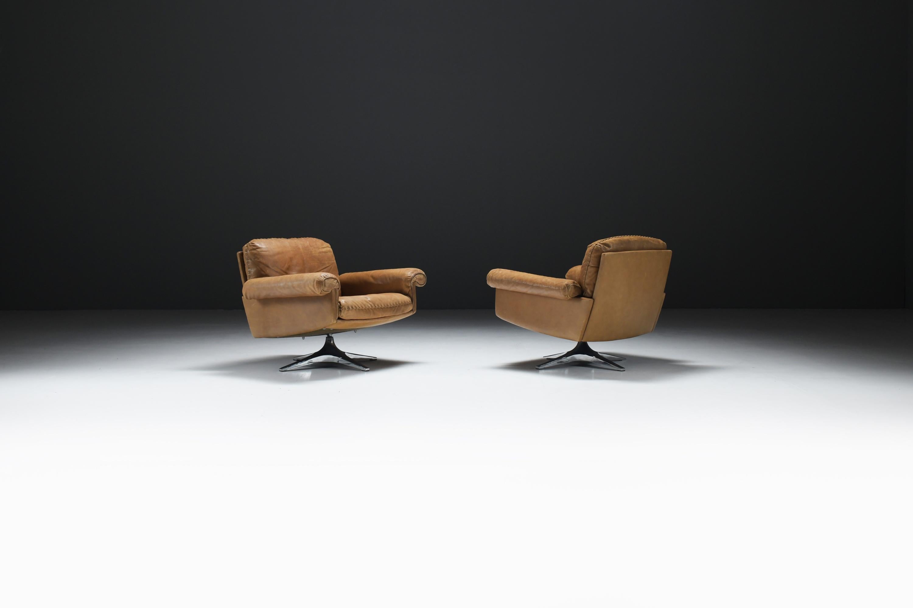 This stunning set of vintage de Sede swivel club chairs boasts a great patina on the luxurious, ultra soft cognac leather upholstery. These high-quality, Swiss-made chairs in this color and condition are a remarkable find on the current