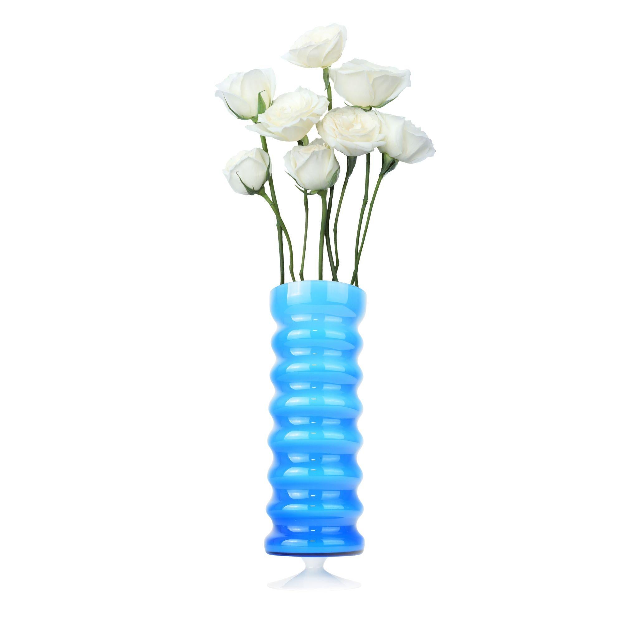 Ce vase Empoli présente un superbe design caractérisé par un dégradé vibrant de teintes bleues, passant d'une nuance plus claire en haut à un bleu plus profond vers le bas. Le vase présente une texture nervurée distinctive, créant une dynamique