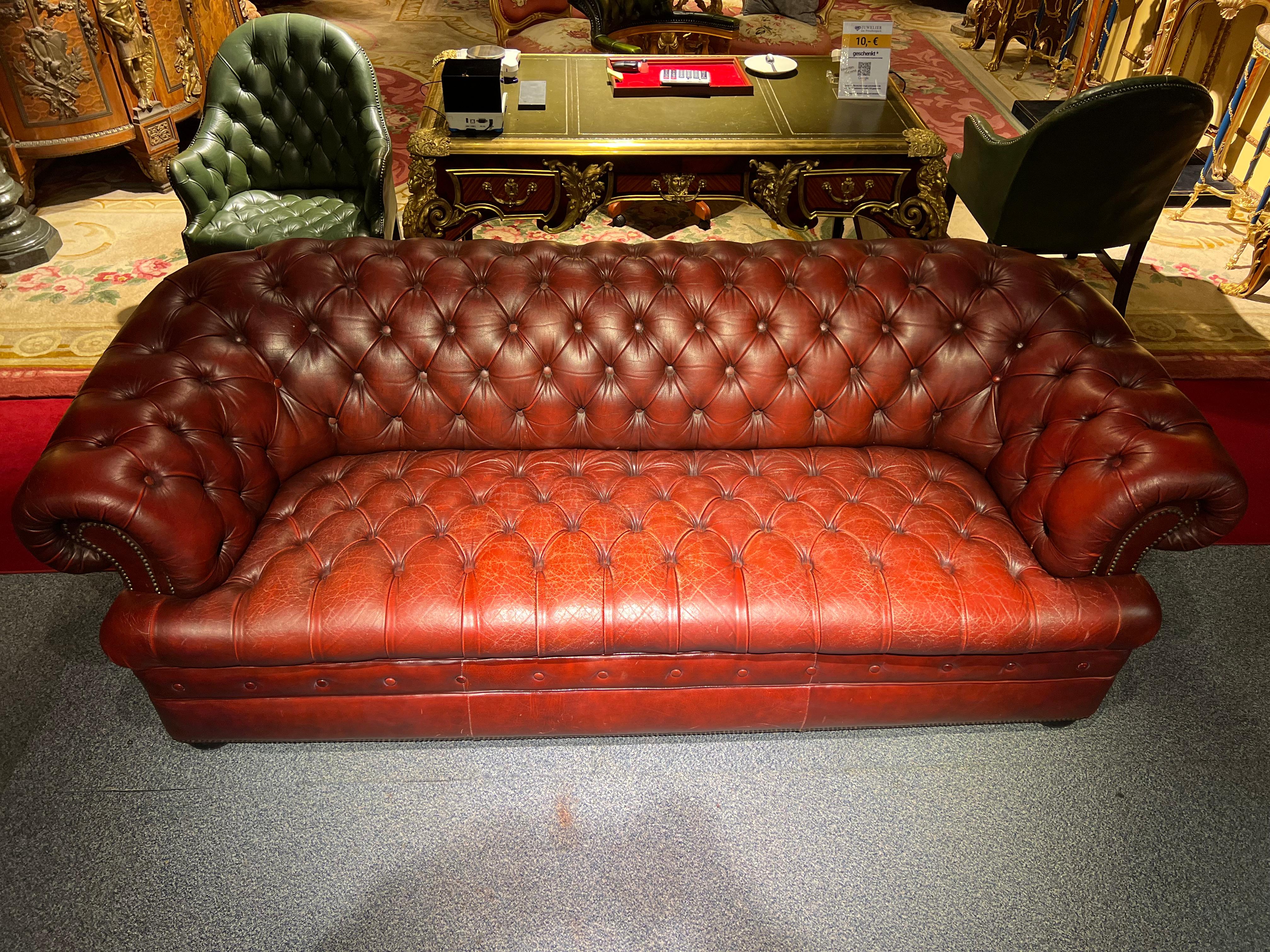 3-seat chesterfield sofa with button tufted detail, circa 1970. Exceptional quality. Double hand-stitching, and applied brass nailhead trim details. The ebonized composite orb feet have been left original, showing wear from age / use. The leather is