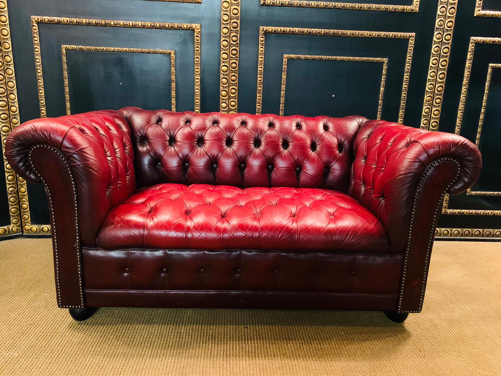 2-seat chesterfield sofa with button tufted detail, circa 1970. Exceptional quality. Double hand-stitching, and applied brass nailhead trim details. The ebonized composite orb feet have been left original, showing wear from age / use. The leather is