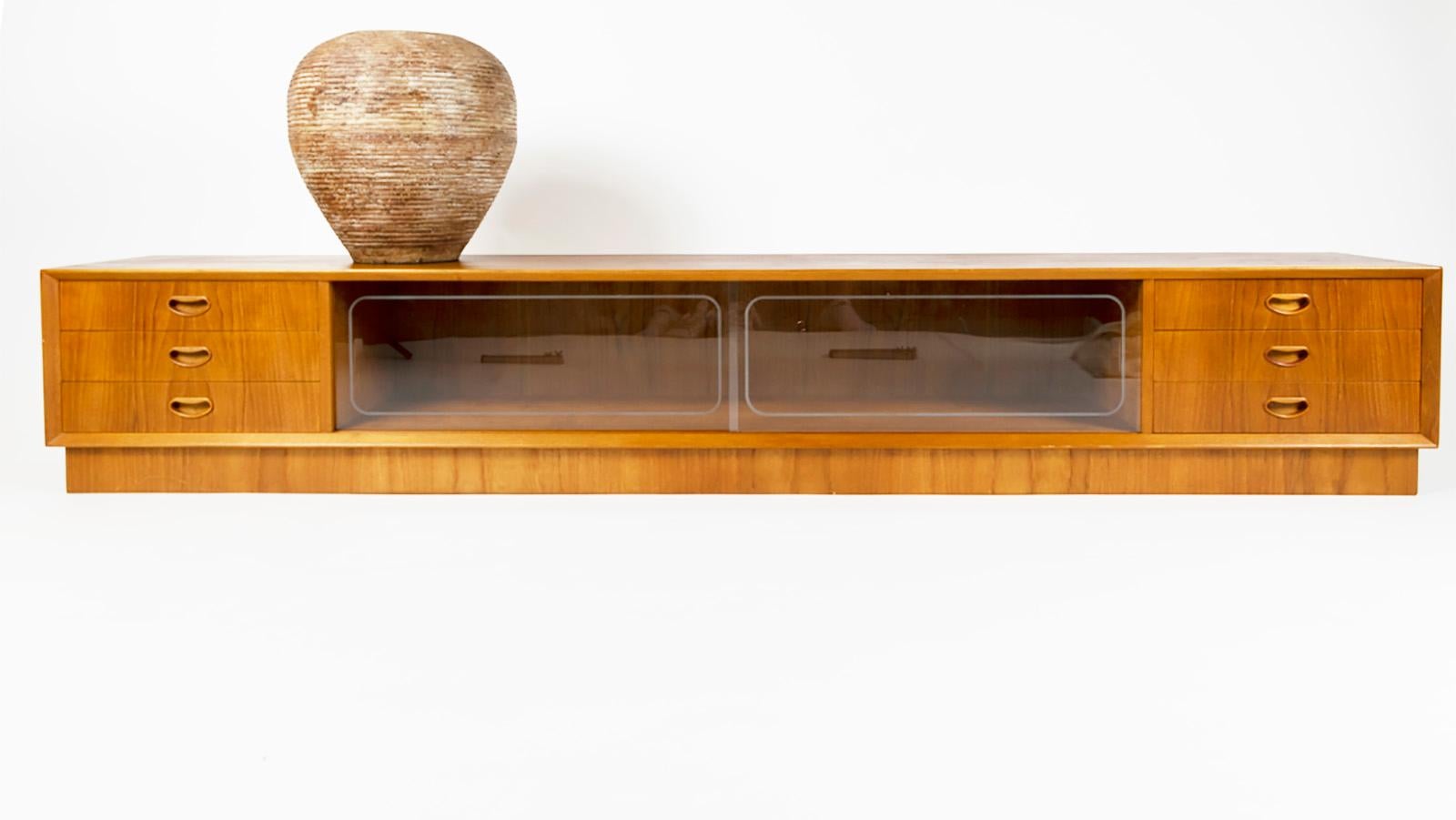 Rare extreme low teak sideboard. 225 cm long!! Stands with 3 drawers on each side, all drawers covered with green fabric. Drawer handles are made of solid teak in the Peter Hvidt style (smiling handles) mid section with 2 engraved glass sliding