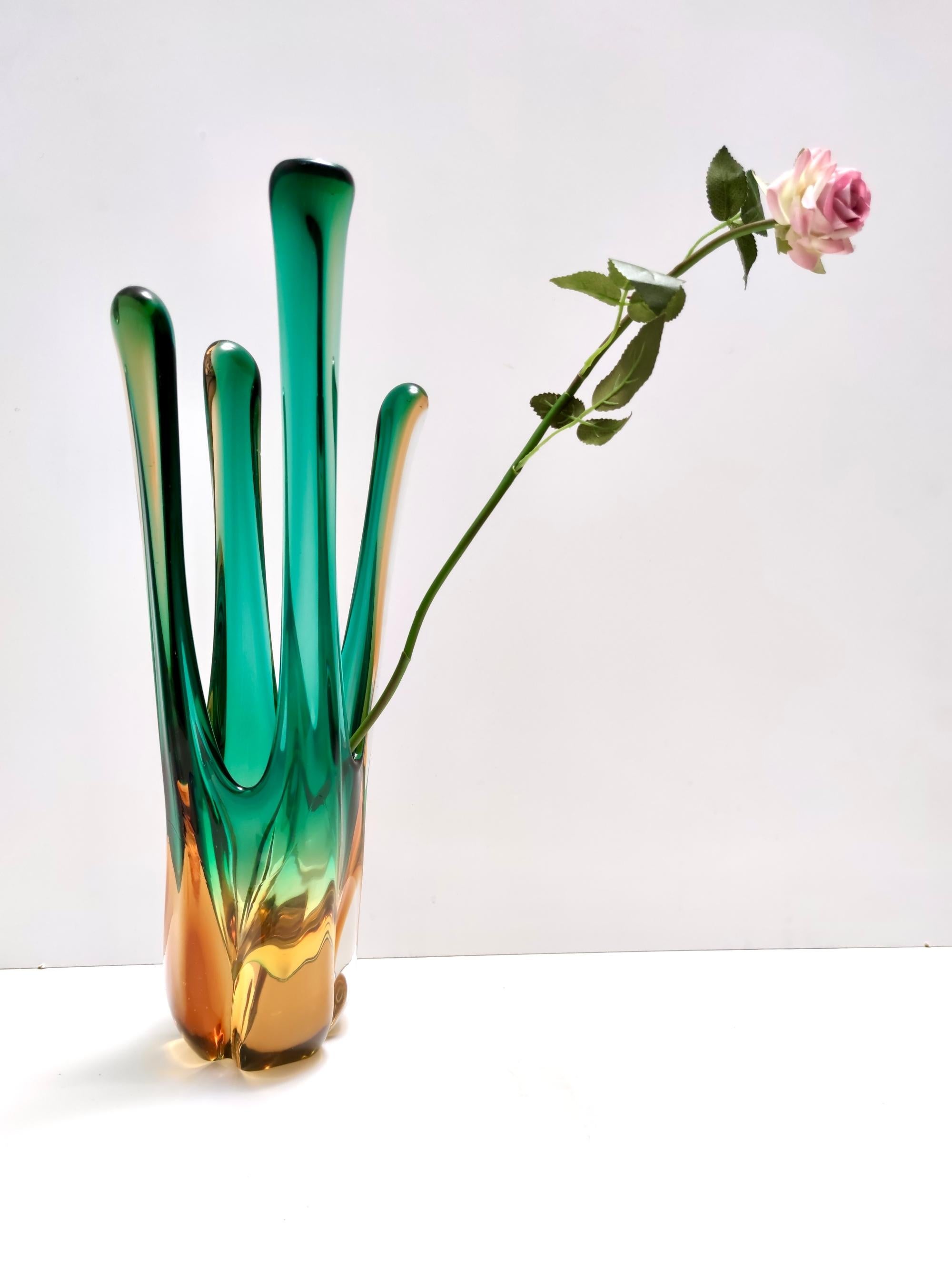 Made in Italy, 1950s - 1960s. 
This beautiful mid-Century modernist Murano glass centrepiece vase is rendered in a lovely green and amber color.
It features a series of elongated arms, creating dynamism and intrigue in the piece, an elegant form