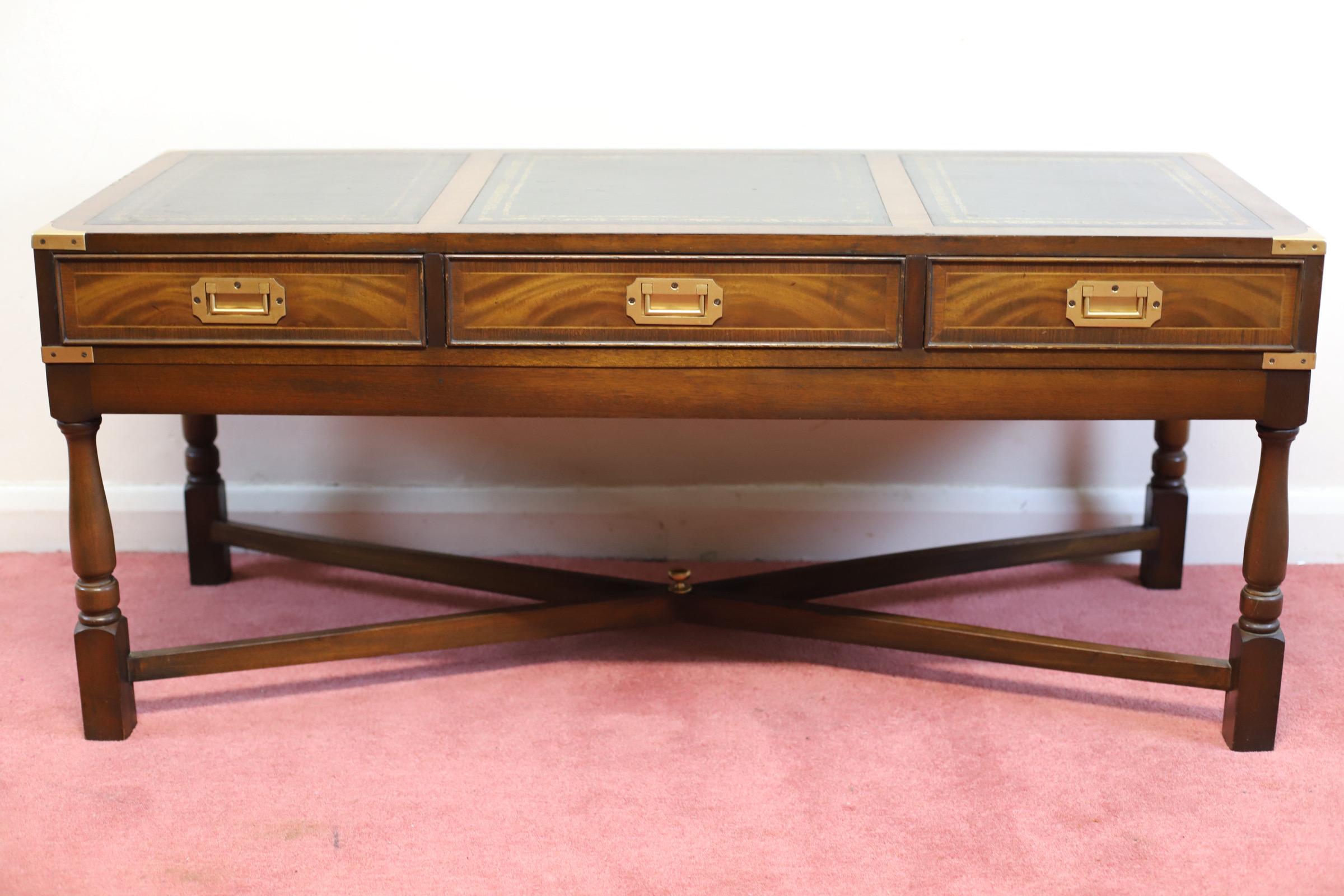 Nous avons le plaisir de proposer à la vente cette ravissante table basse en acajou et laiton de style Campaigner, avec un plateau en cuir noir séparé en trois parties, trois tiroirs ouvrants avec des poignées en laiton insérées, des courroies