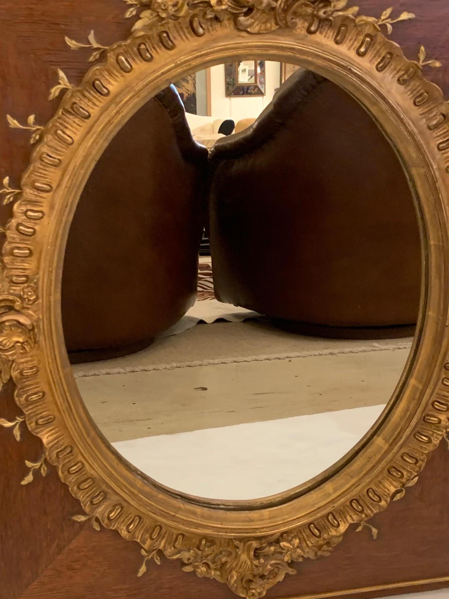 Miroir vintage très inhabituel ayant un fond rectangulaire en chêne et un miroir central ovale en bois doré au premier plan. Un décor en bois doré assorti orne la périphérie du bois.
Le miroir lui-même mesure 19 H x 15 W.