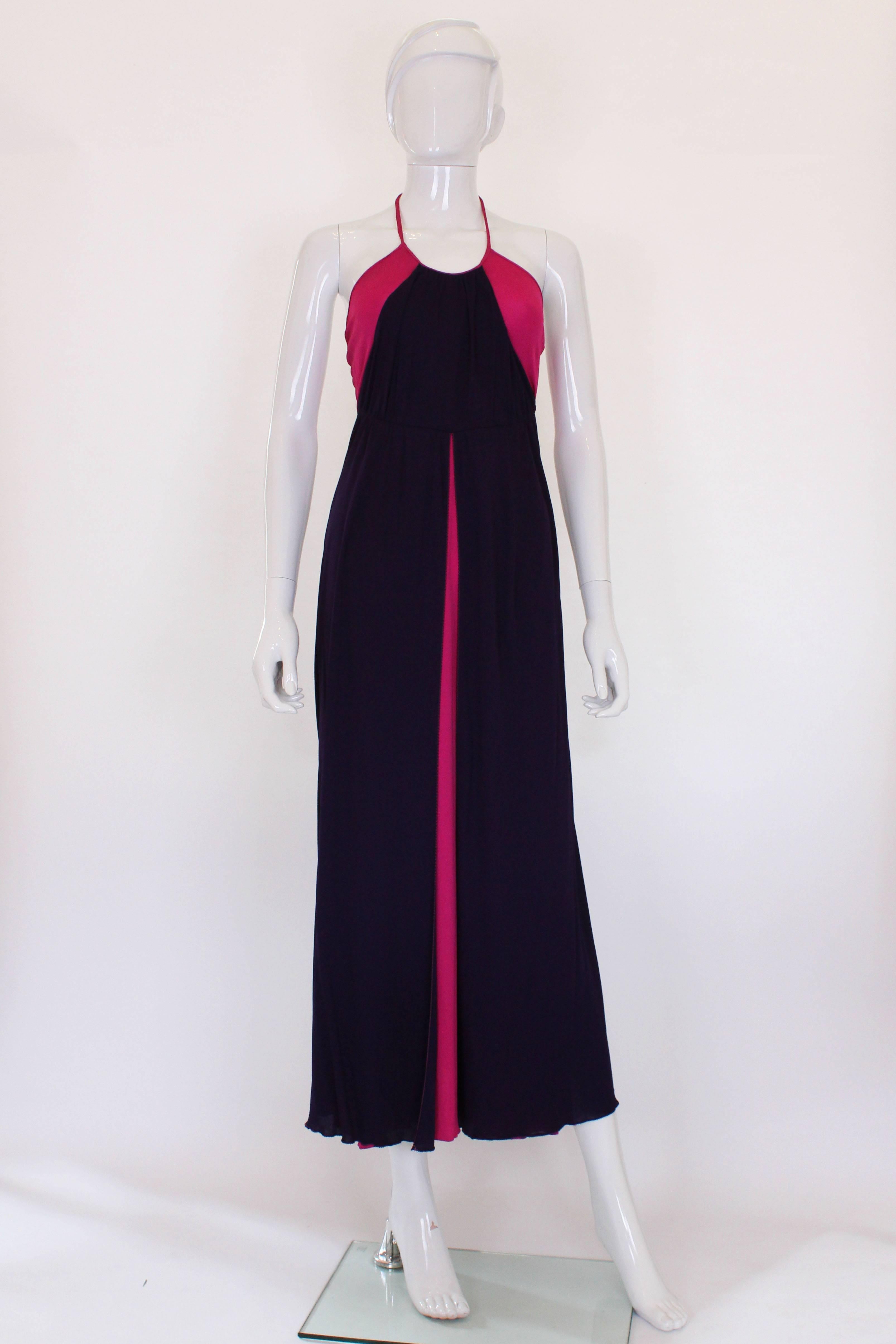 A glamorous gown from the 1970s by British designer Bruce Oldfield.
In a stunning colour clash of bright pink and deep purple,this gown is a real head turner. It has a halter neck ,and central back zip.The column dress is bright pink with a deep