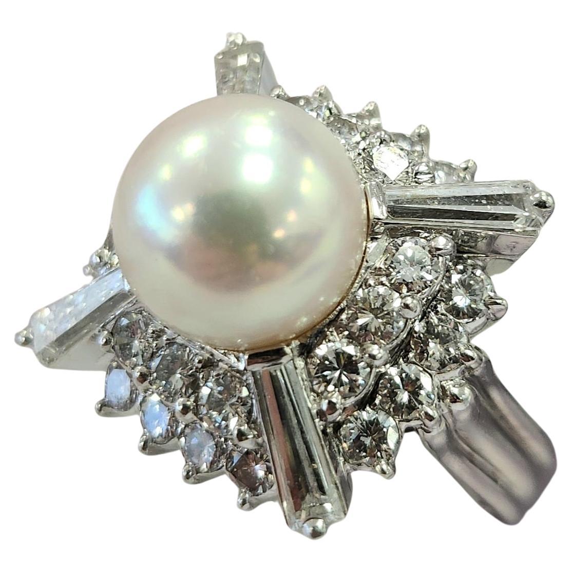 Ein bezaubernder weißer Perlenring mit 4 länglichen Baguette-Diamanten und 2 kaskadenartigen Ebenen runder Diamanten.
✨ Design-Highlights:

Eine atemberaubende 9,8 mm große weiße Perle, die einen sanften rosa Farbton ausstrahlt.
Vier längliche,