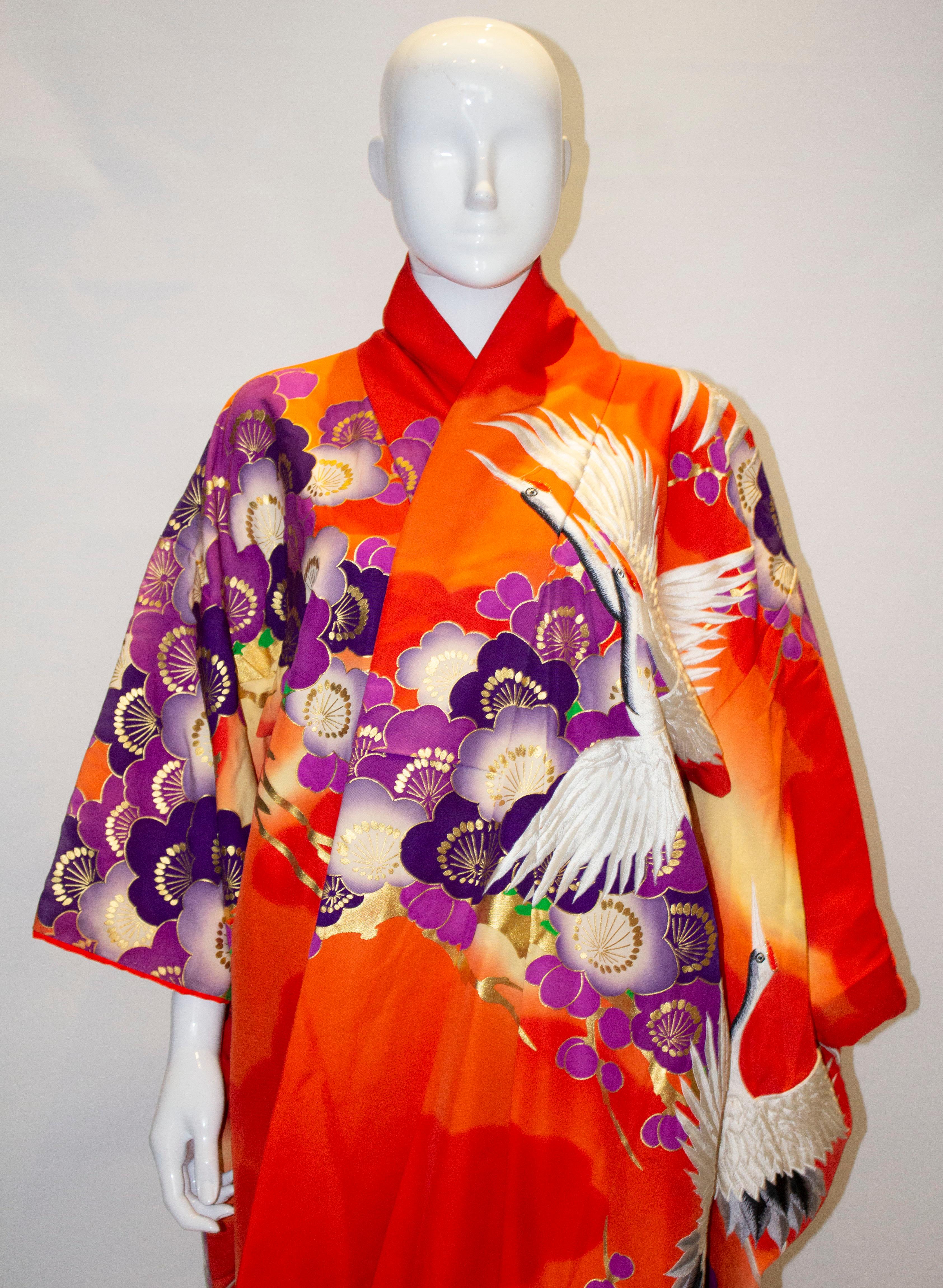 A headturning wedding kimono dating from the 1980s. The kimono has some wonderfu embroidery with a crane theme.  It has a red back ground, with gold, purple and green decoration, and is lined in red. It will fit a bust up to 50'' length 74''