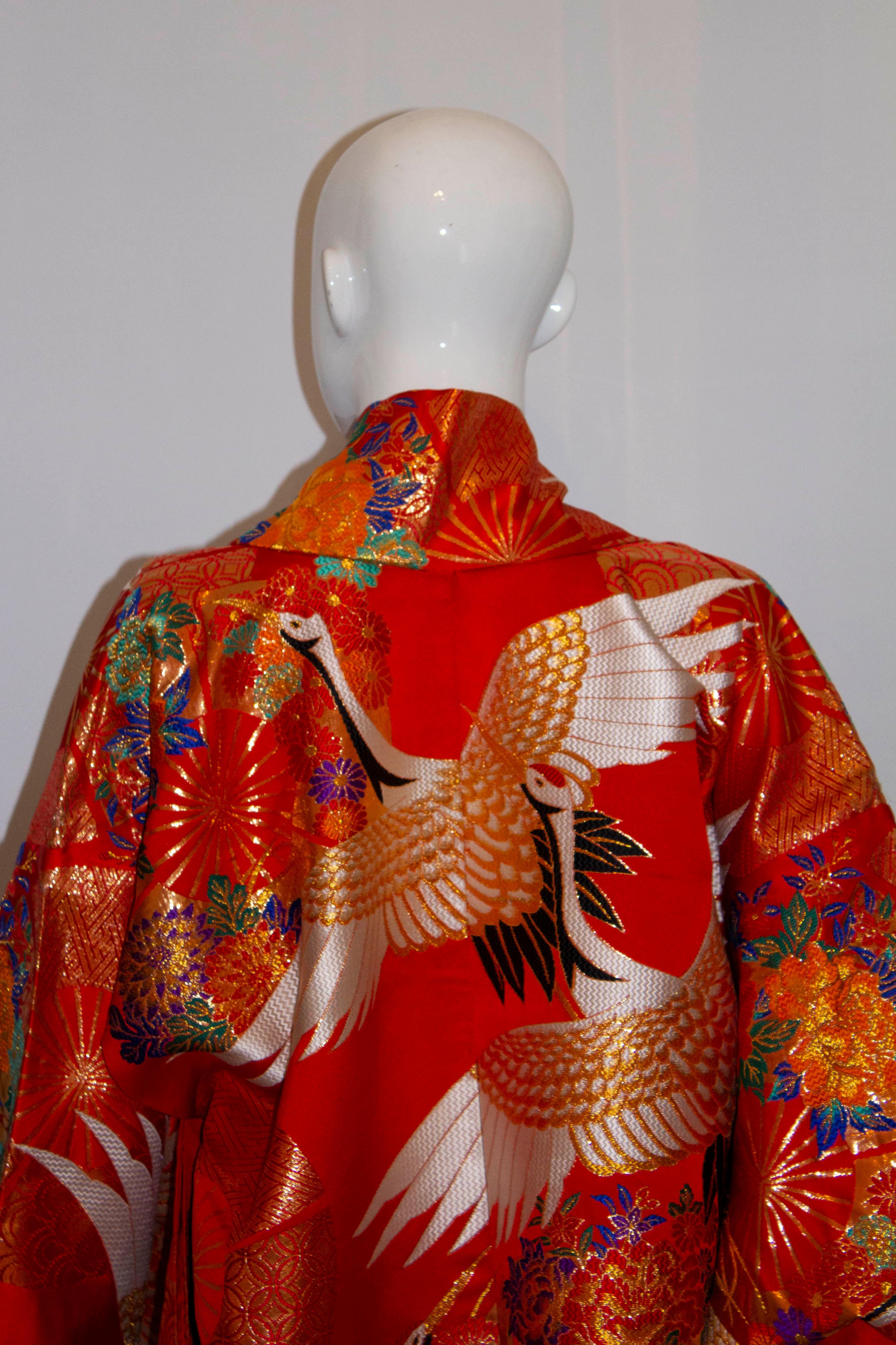 A stunning vintage wedding kimono, in a wonderful scarlet colour , heavily embroidered with white and gold cranes flying through clouds. Cranes mate for life and are a fortuitous symbol representing harmony in a relationship and longevity. The hem