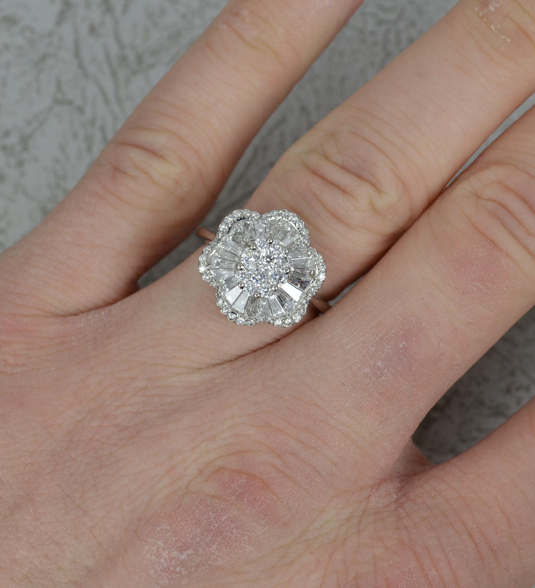 
A very striking diamond cluster ring.

Solid 18 carat white gold example.

Flower head shape cluster ring comprising of round brilliant and tapered baguette cut diamonds. Vs clarity, f-g colour. 1.75 carats total.

14mm x 15mm cluster