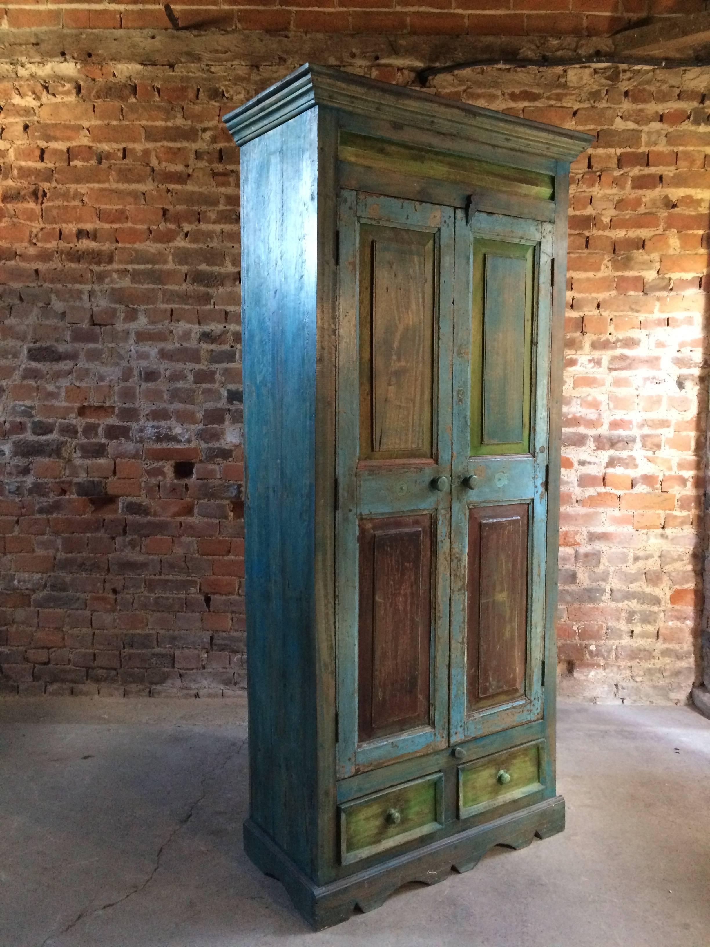 A beautiful mid-20th century French painted housekeepers cupboard or wardrobe in the rustic style, painted in blue and green grounds with heavily distressed finish, the corniced top over two panelled doors with double shelves within over to small