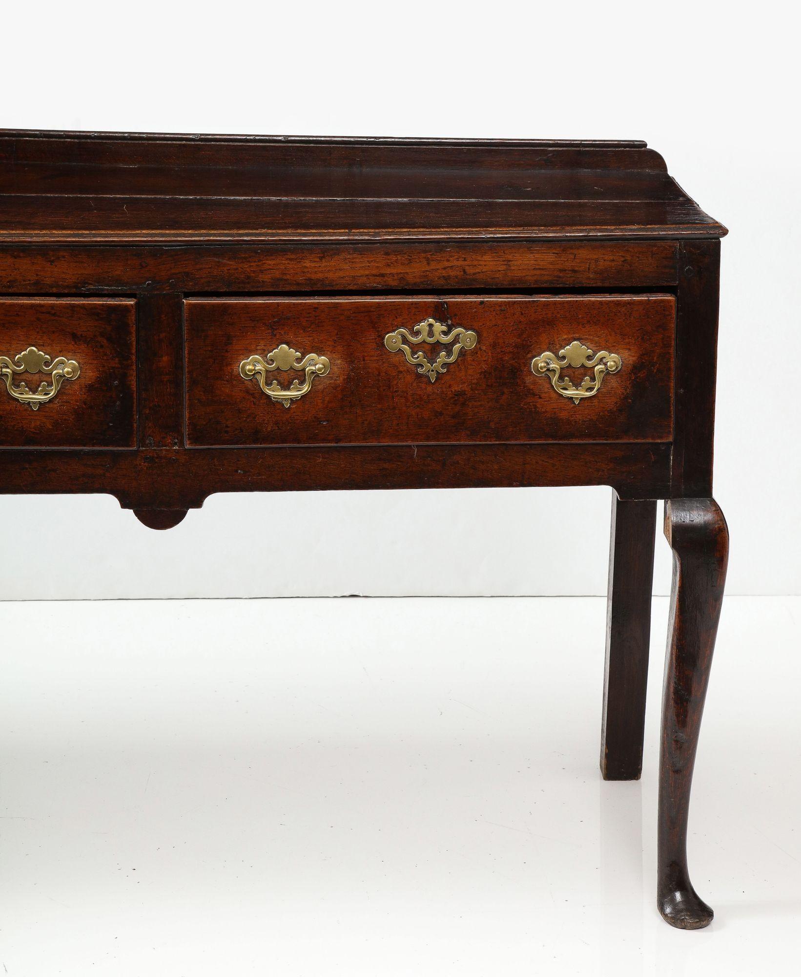 Fine early 18th century Welsh low dresser, the molded top with shallow backsplash, over three drawers with scalloped drops along straight apron and standing on graceful cabriole legs, the whole possessing fantastically rich patination, great scale