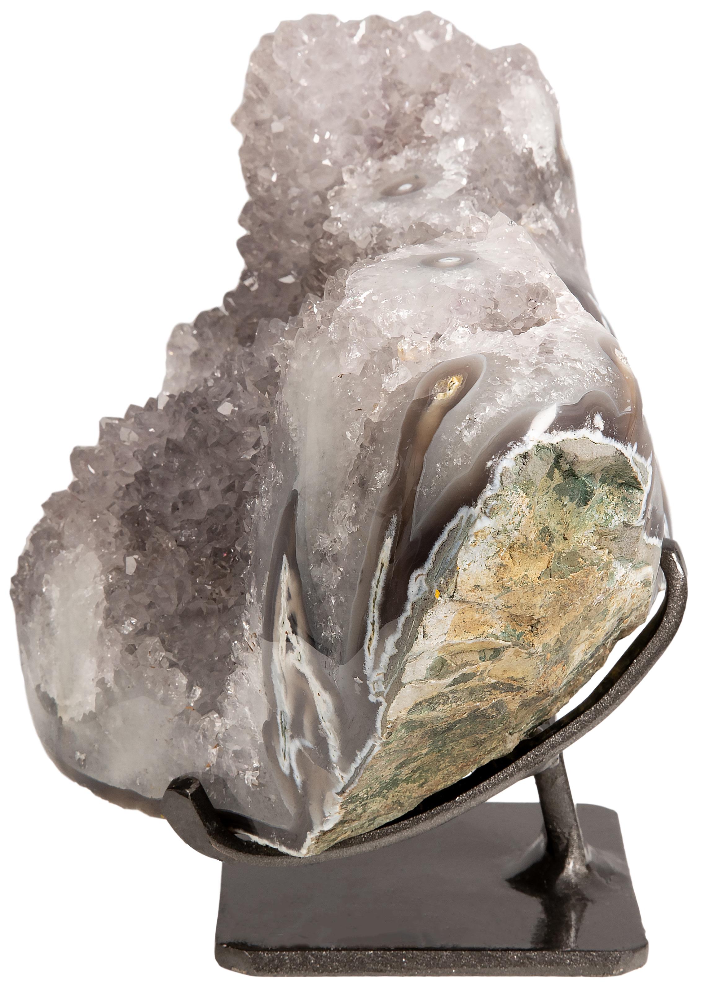 This piece comprises of a stunning example of white quartz, elegantly displayed on a metal stand, with a naturally decorative multiple stalactite adornment. 

The polished borders of the formation allow one to appreciate the visible grey, brown