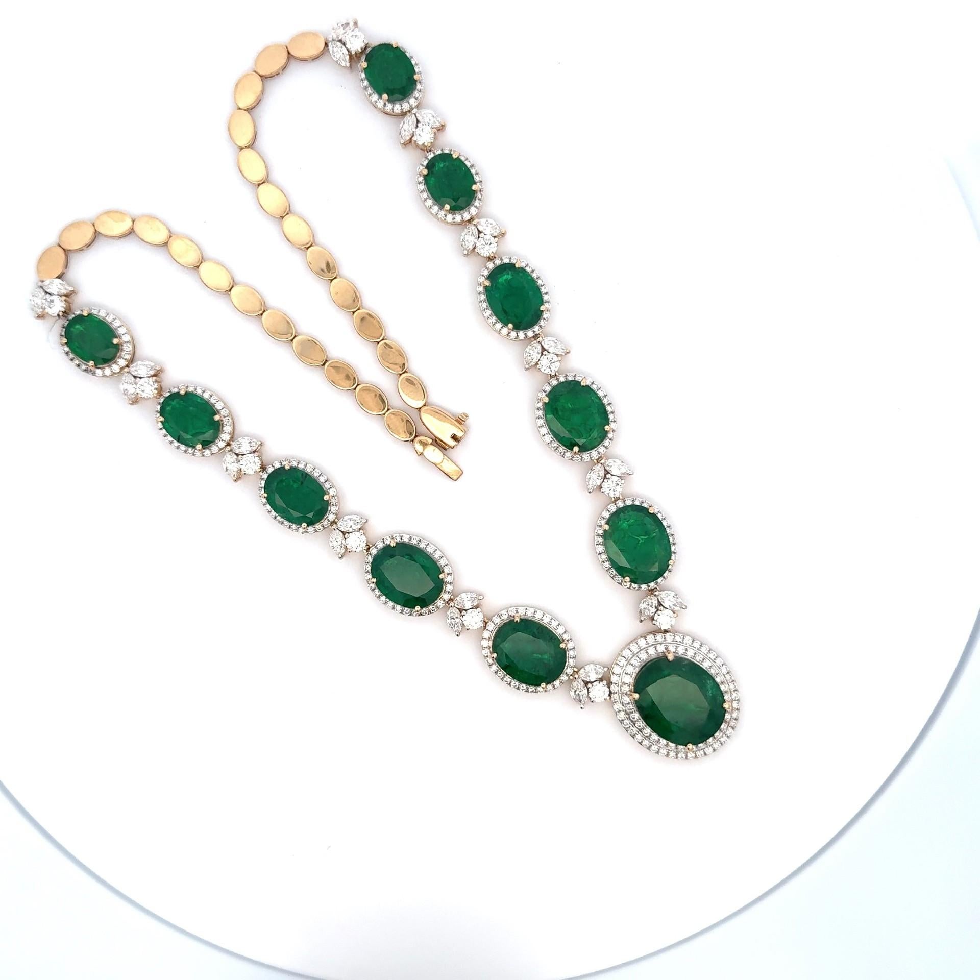 Le luxueux collier présente une rangée de gros diamants de 45 carats, de couleur bleu foncé.  émeraudes zambiennes de forme ovale serties dans une monture en or jaune 18 carats au design complexe. La combinaison de l'émeraude zambienne d'un vert