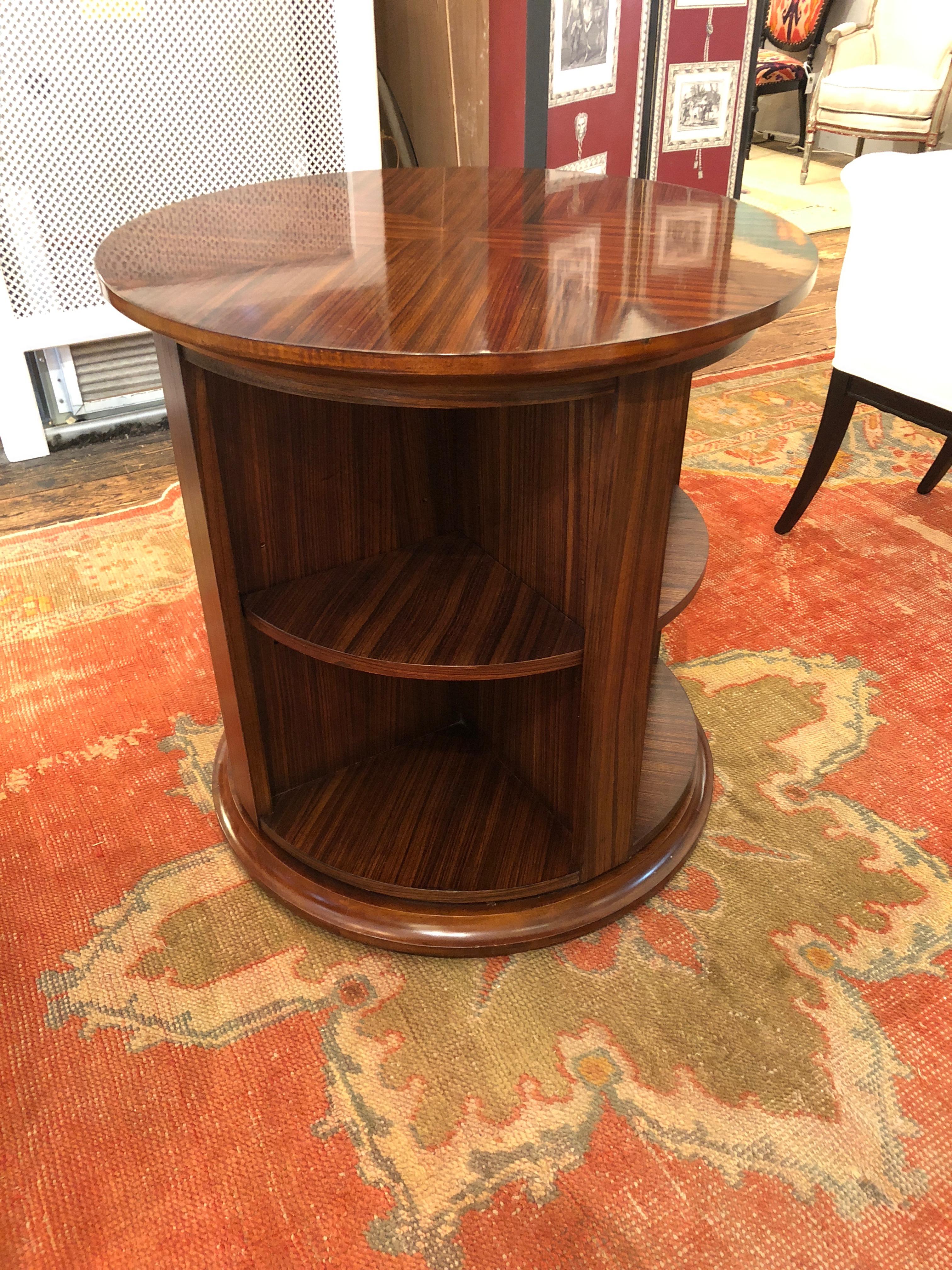 Handsome circular rotating library table in a beautiful grained zebrawood having triangular shelves around the periphery.