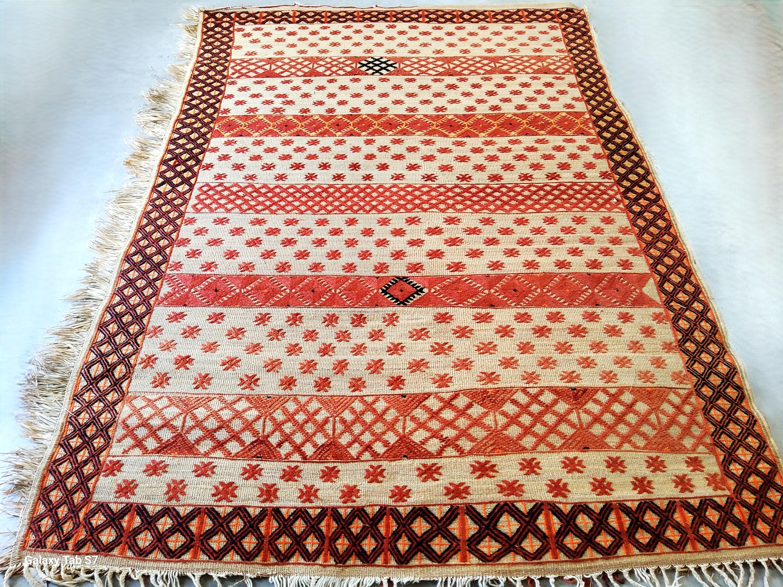 Rara stuoia berbera vintage realizzata a mano in Marocco nel 1982. Questo tappeto tribale (260 x 180 cm) è un esempio autentico di artigianato sahariano, intrecciato con giunco naturale e dettagli in lana. I materiali, scelti per resistenza e