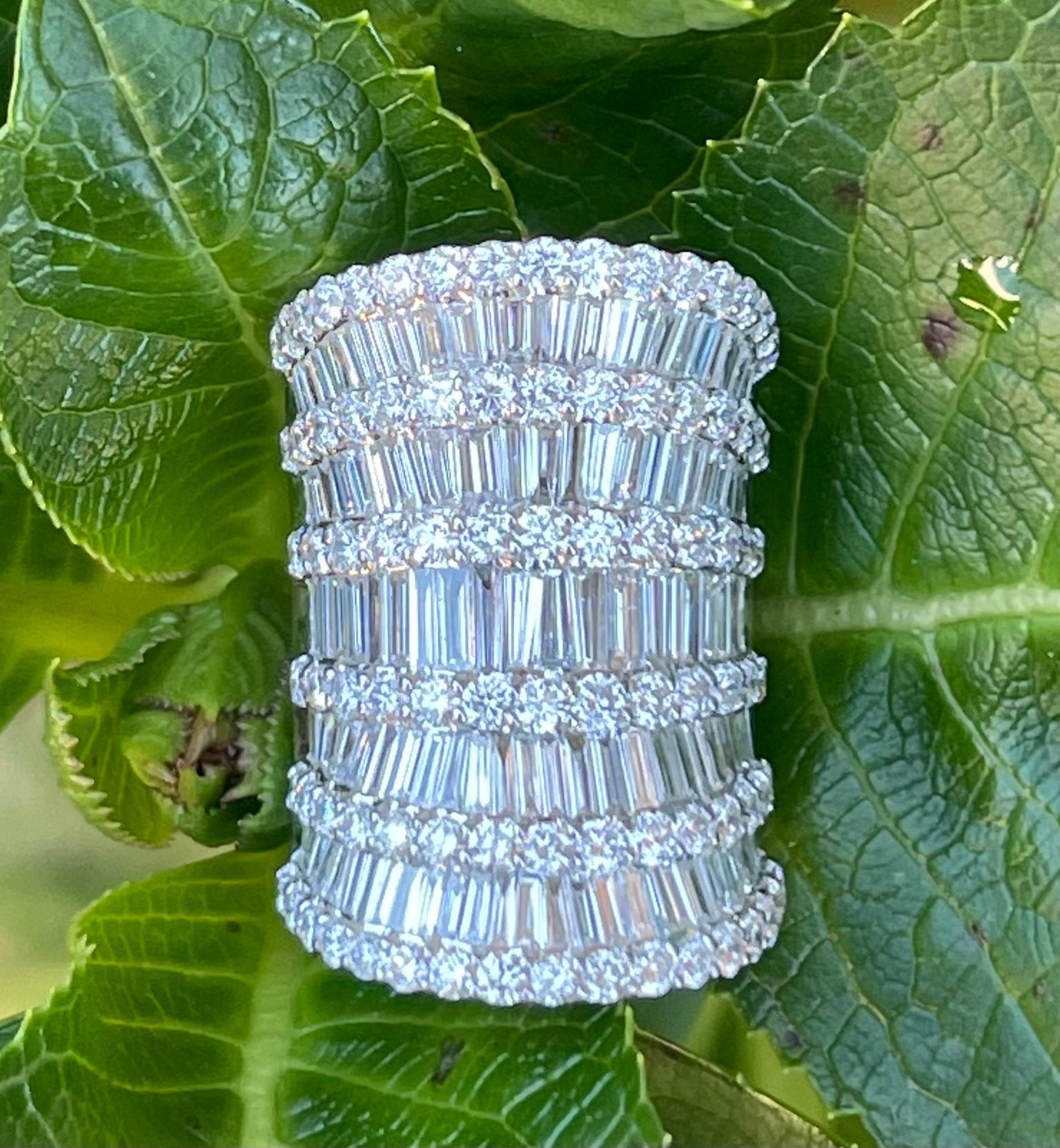 Magnificent and stupendous, very white diamond cocktail ring features 5 rows of sparkling white baguette diamonds which are invisibly set and separated by 6 rows of prong set white diamonds. This ring has a very unique concave shape, with rounded