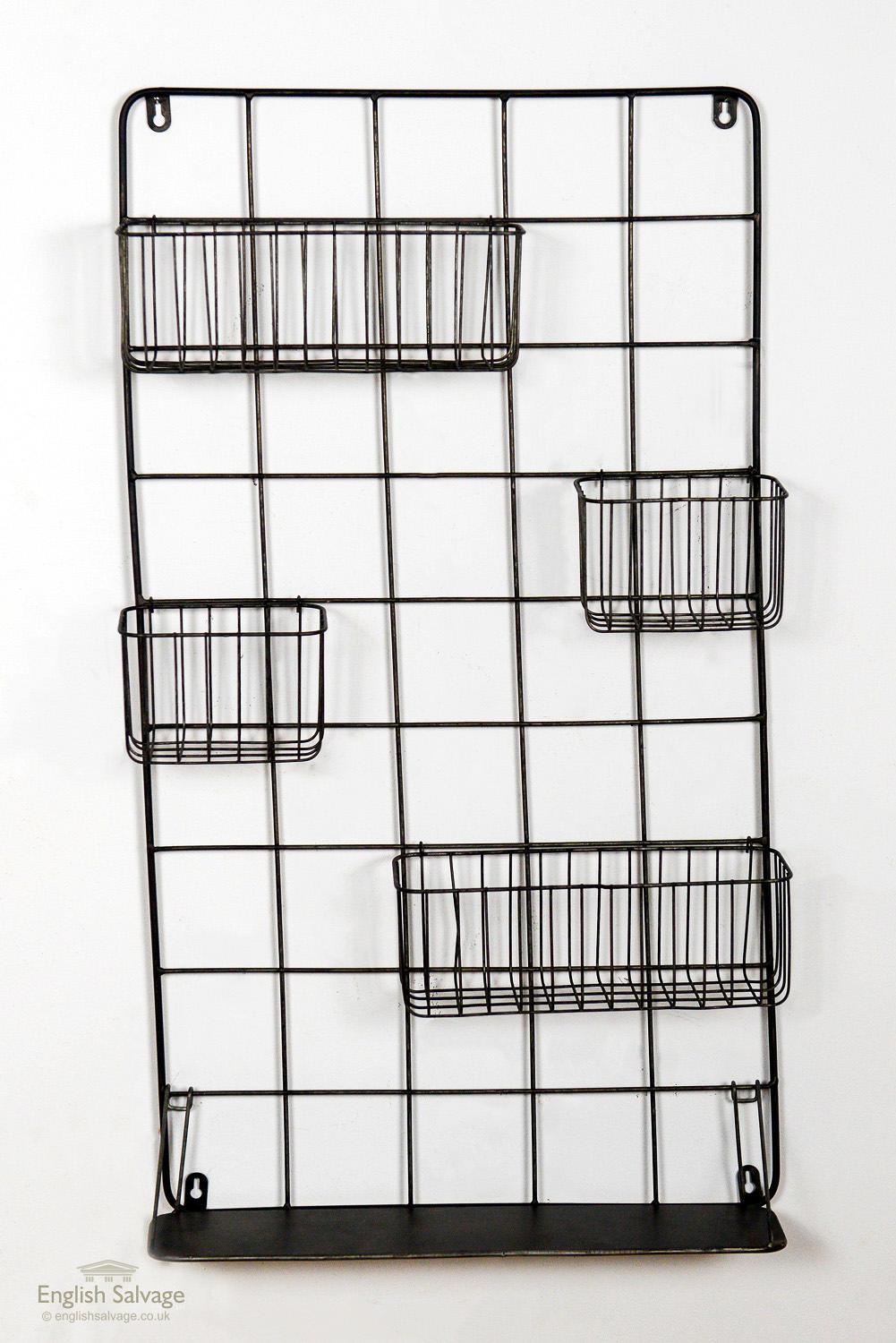 Sturdy wire wall rack with four various sized baskets and a flat shelf, complete with four hanging fasteners.