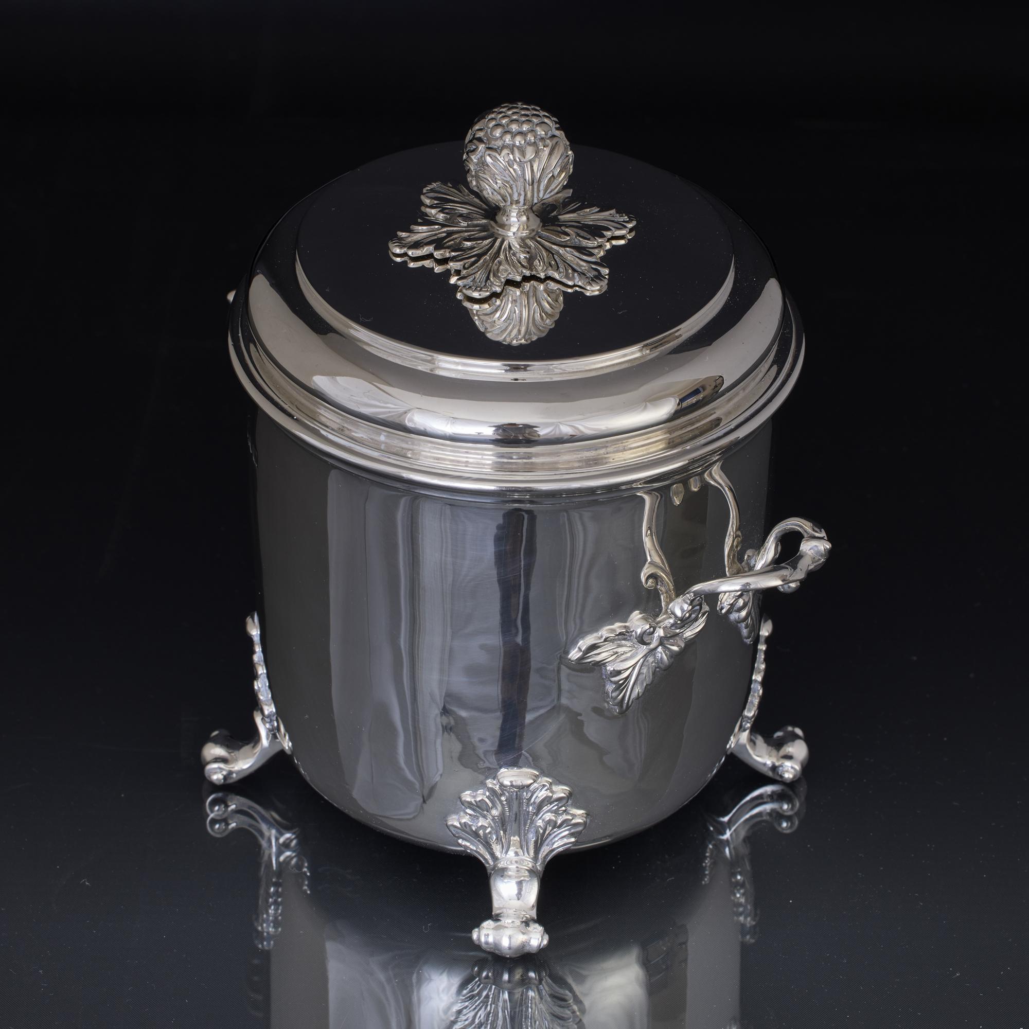 Substantial two-handled, cylindrical, antique silver container with a pull off cover and mounted on four cast scroll and acanthus leaf supports. The two cast handles are fittted to the box with decorative leaf fastenings, while the cover has a