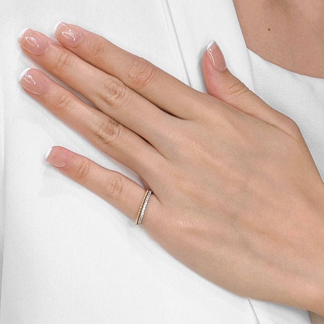 Portez à la main cette bague d'une simplicité stupéfiante, délicatement réalisée en or bicolore 18 carats. Une rangée continue de vingt-trois diamants ronds naturels brillants, totalisant 0,18 carat, délicats mais accrocheurs, orne ce bracelet