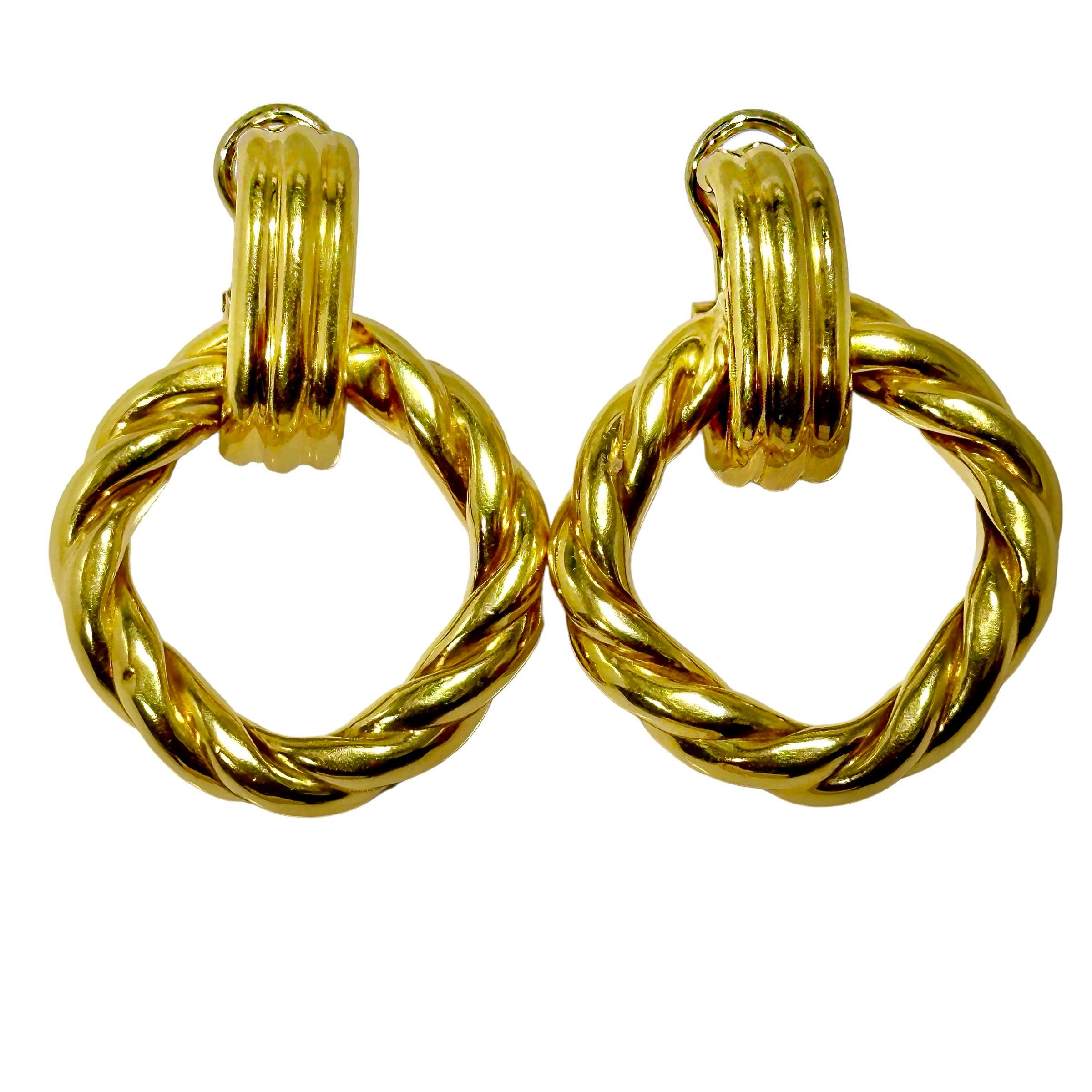 Un paio di orecchini pendenti facili da indossare, casual ed eleganti, in oro giallo 18 carati. Le cime scanalate corrono da nord a sud, da cui è sospeso un cerchio di corda intrecciata. La parte inferiore degli orecchini misura 1,5 cm di diametro.
