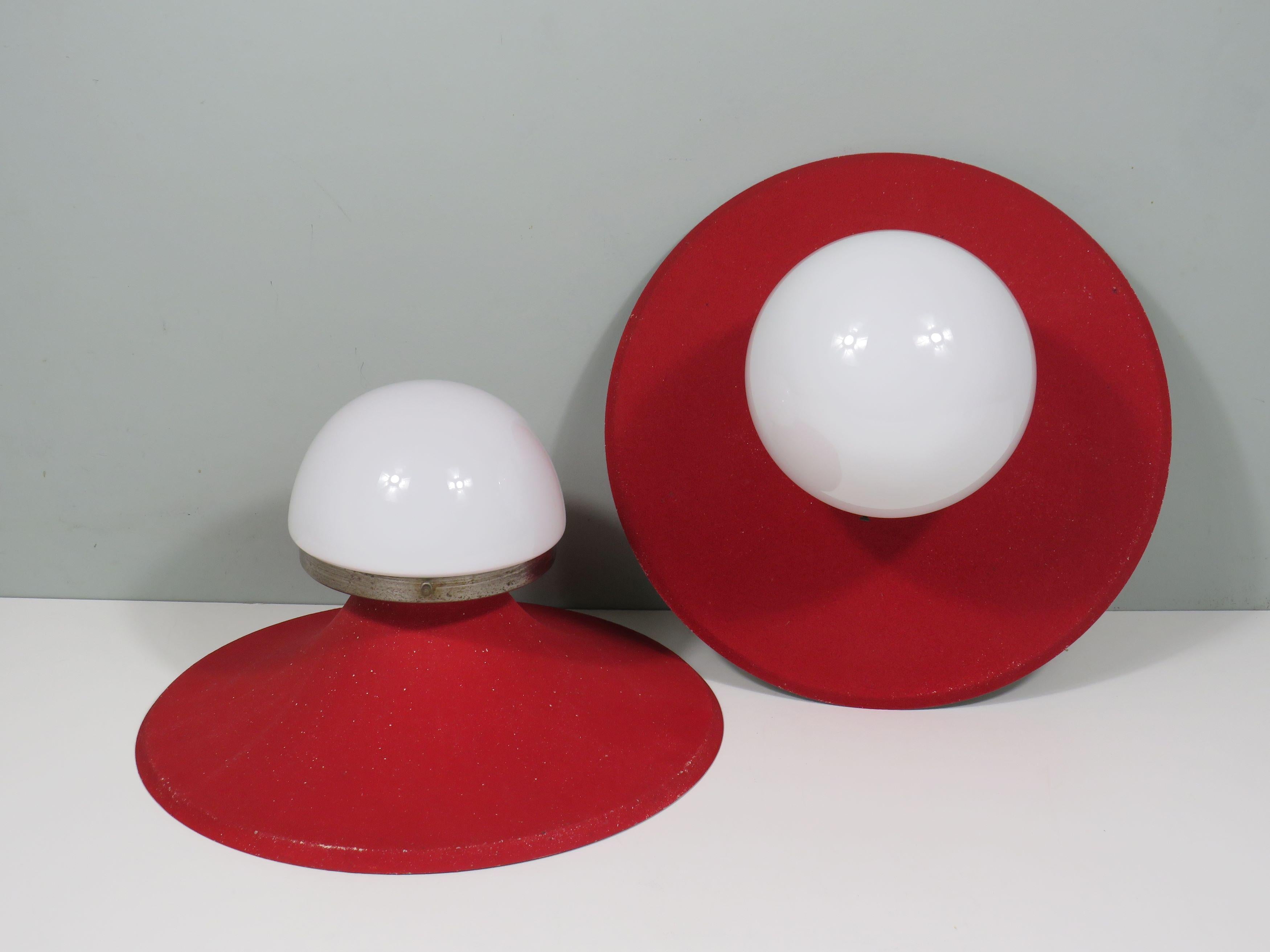 Con le loro linee metalliche fluide e la vernice rossa granulosa, queste originali lampade da parete emanano un inconfondibile stile anni '50. Il pregiato vetro bianco fornisce una luce soffusa, rendendo queste lampade eleganti e funzionali al tempo