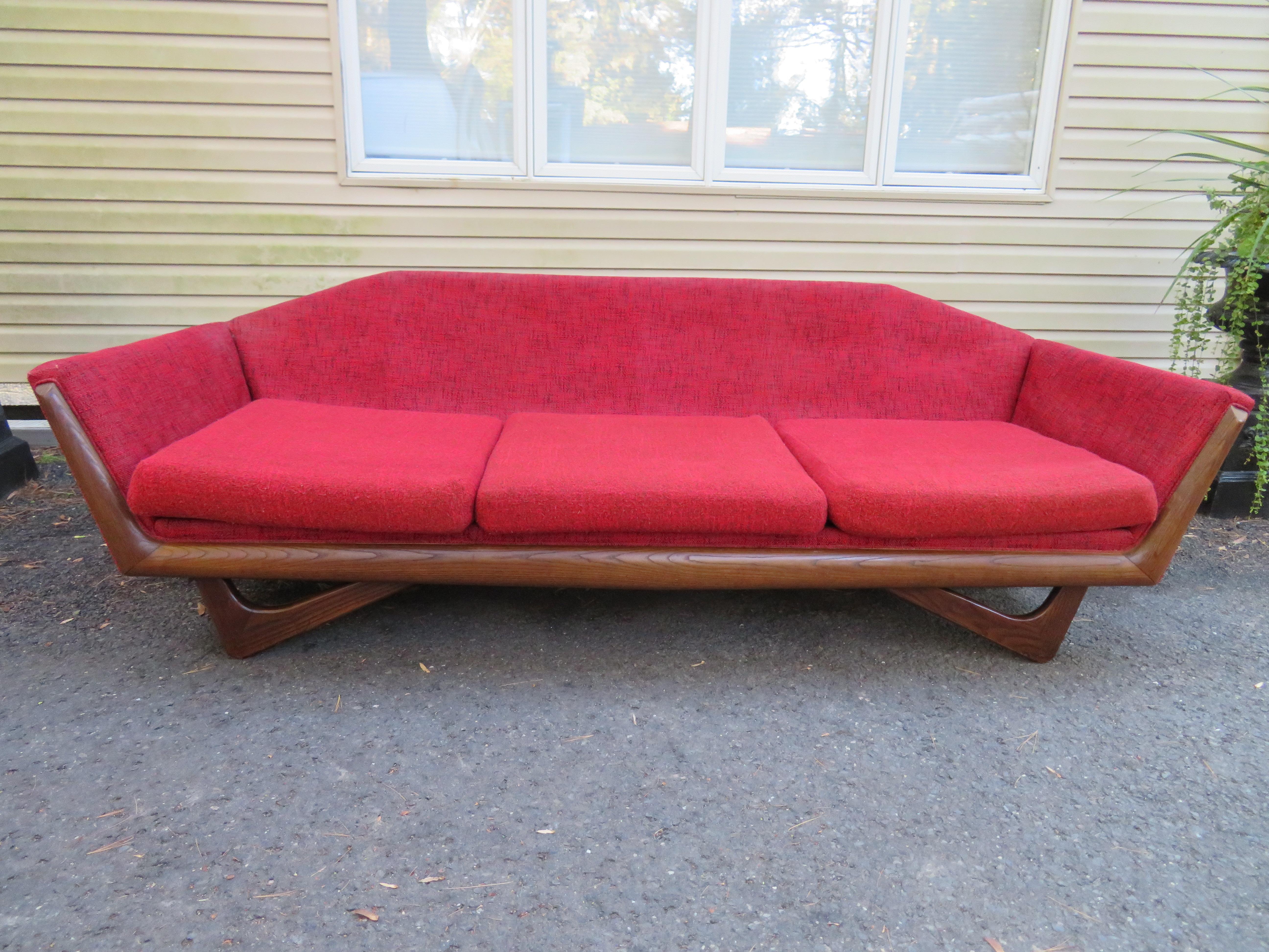 Elegante sofá escultural de nogal estilo Adrian Pearsall. Conserva su tela original, que muestra los años, por lo que recomendamos volver a tapizarla. Los cojines florales del respaldo son los originales y son los que se incluyen en esta venta, los