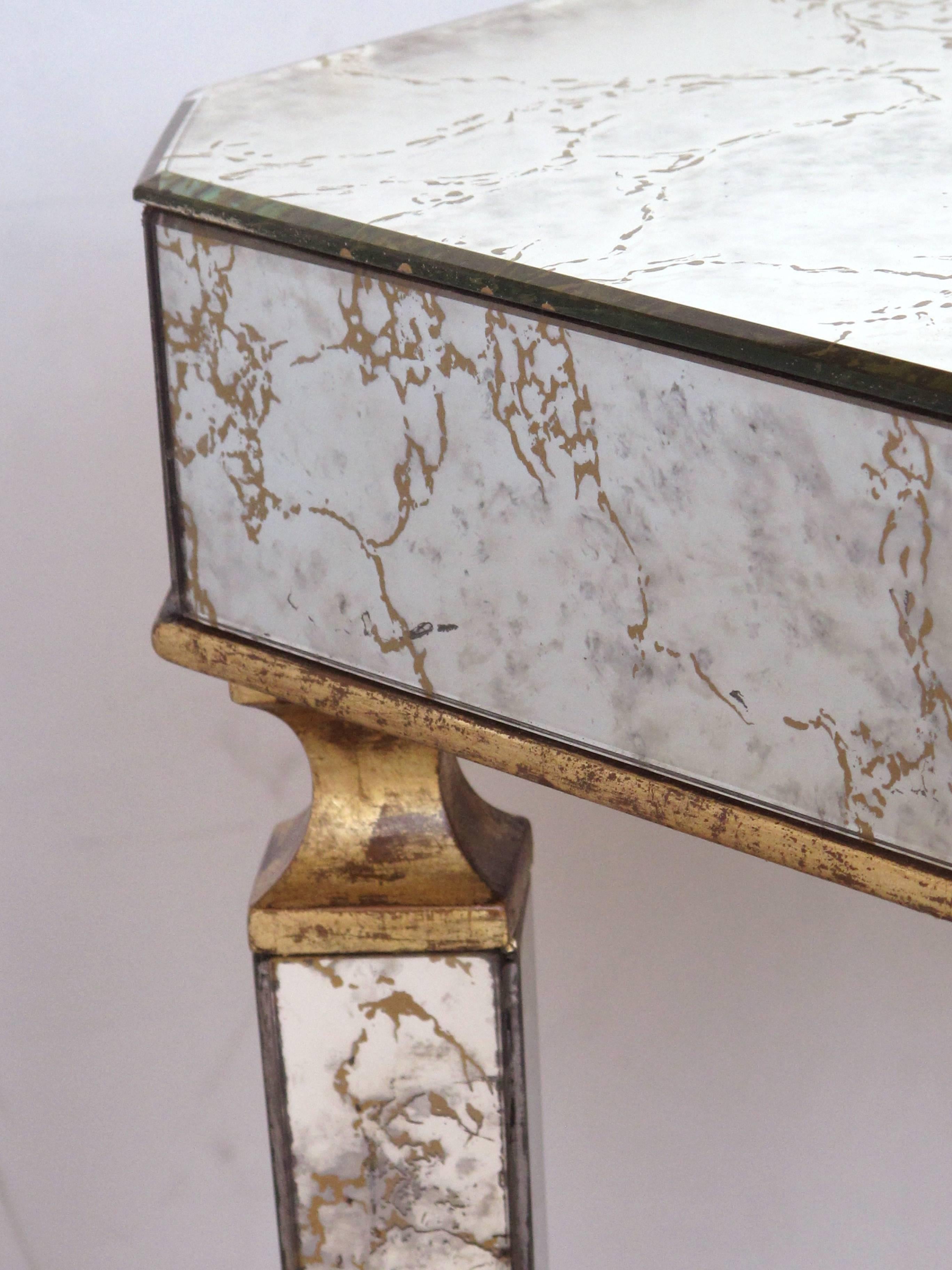 A stylish American midcentury rectangular mirrored side/end table with gilt-wood highlights by Archibald Taylor; the rectangular top with canted corners raised on tapering quadrangular supports; veneered with mirrored plates with gold veining.