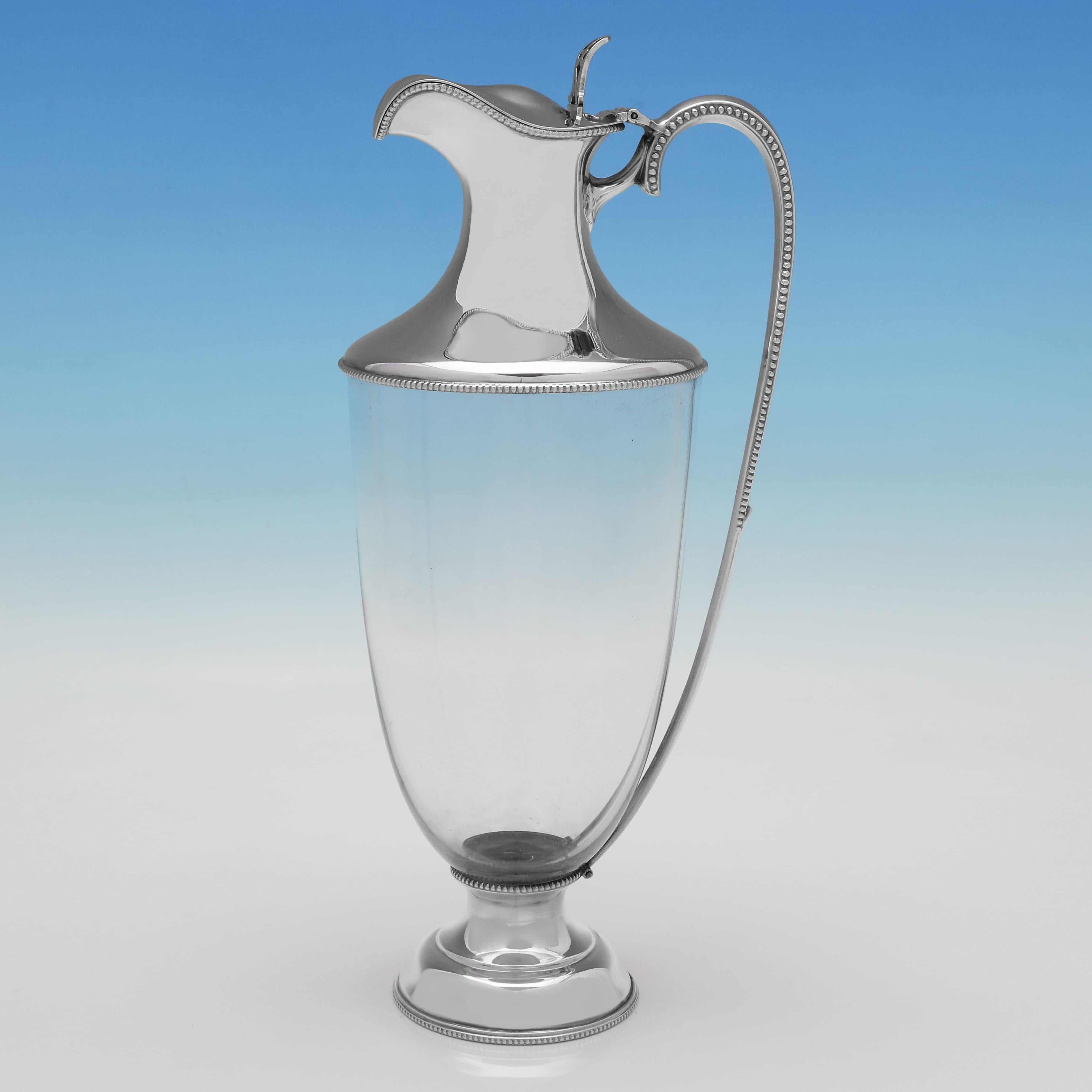 Hallmarked in Sheffield in 1918 by Walter & Charles Sissons, this very handsome pair of George V period, Antique Sterling Silver Claret Jugs, are urn shaped, and feature plain glass bodies, and silver mounts, bases and handles with bead borders.