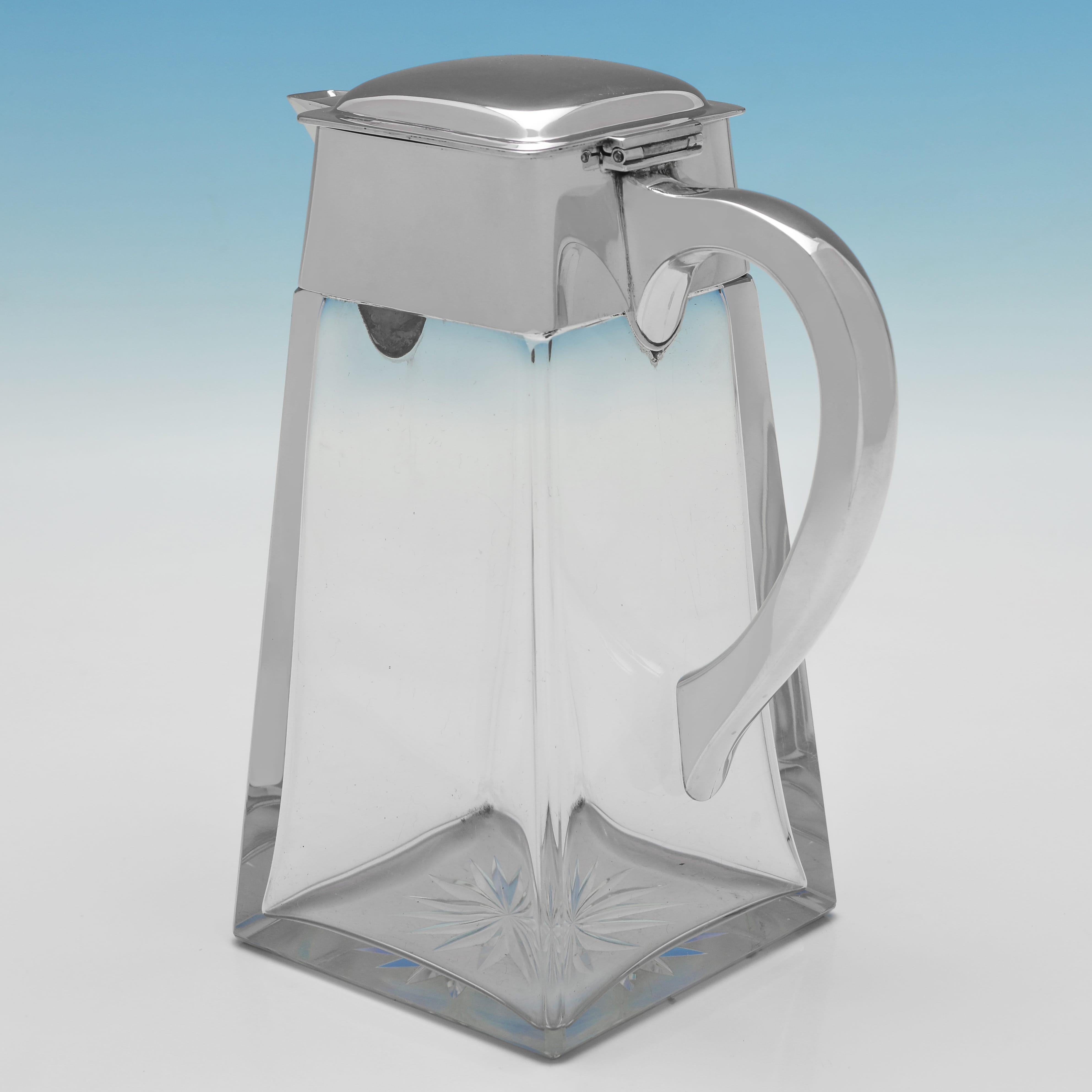 Marcada en Londres en 1906 por Heath & Middleton, esta elegante Jarra de Clarete de Plata de Ley Antigua tiene un cuerpo de cristal cuadrado con lados afilados y una montura y asa de plata lisa. La jarra de clarete mide 19,5 cm de alto, 15 cm de