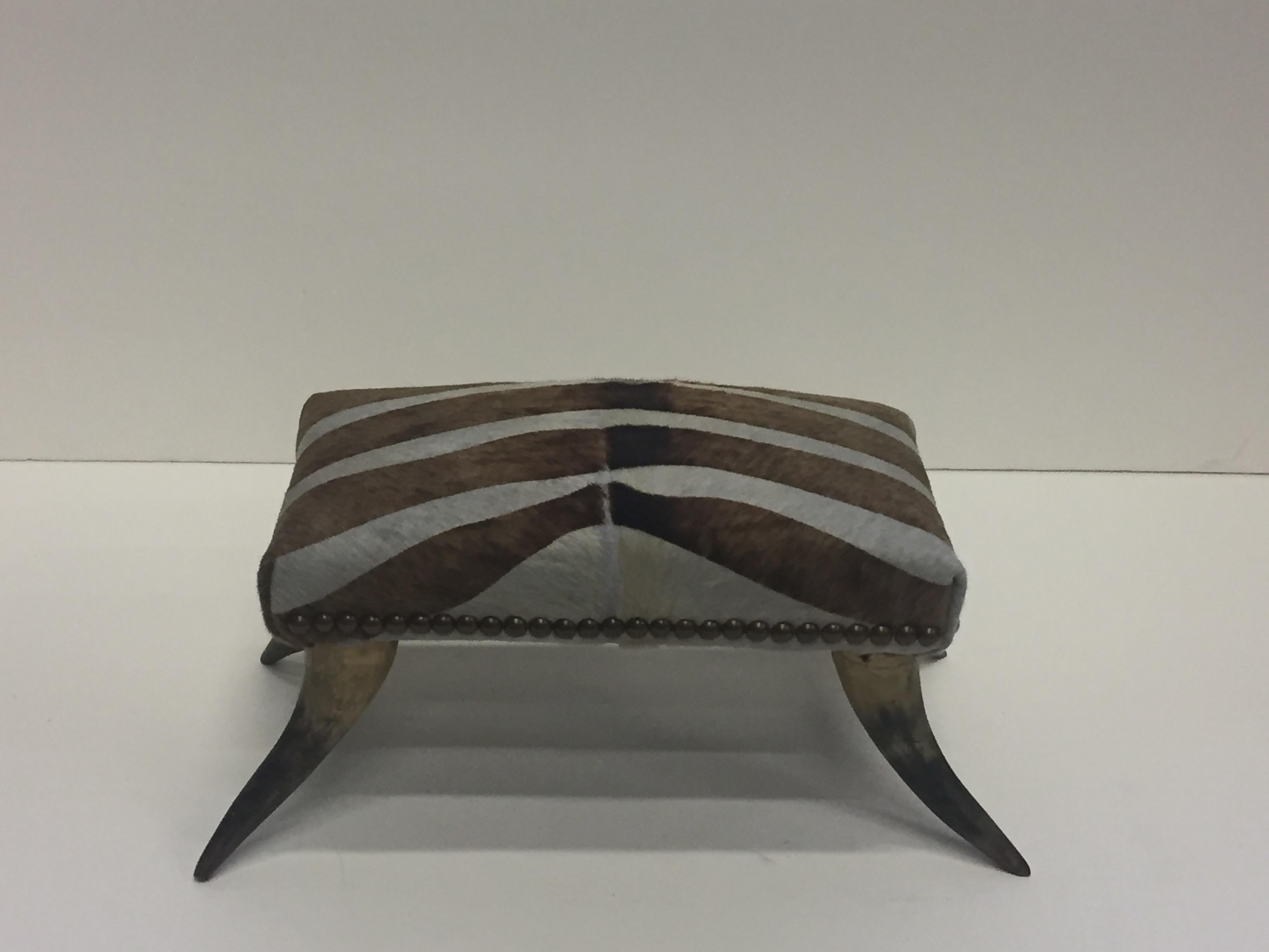A wonderful and functional Victorian footstool from the late 19th century having
authentic horn feet and new upholstery in brown and white cowhide zebra stripe.