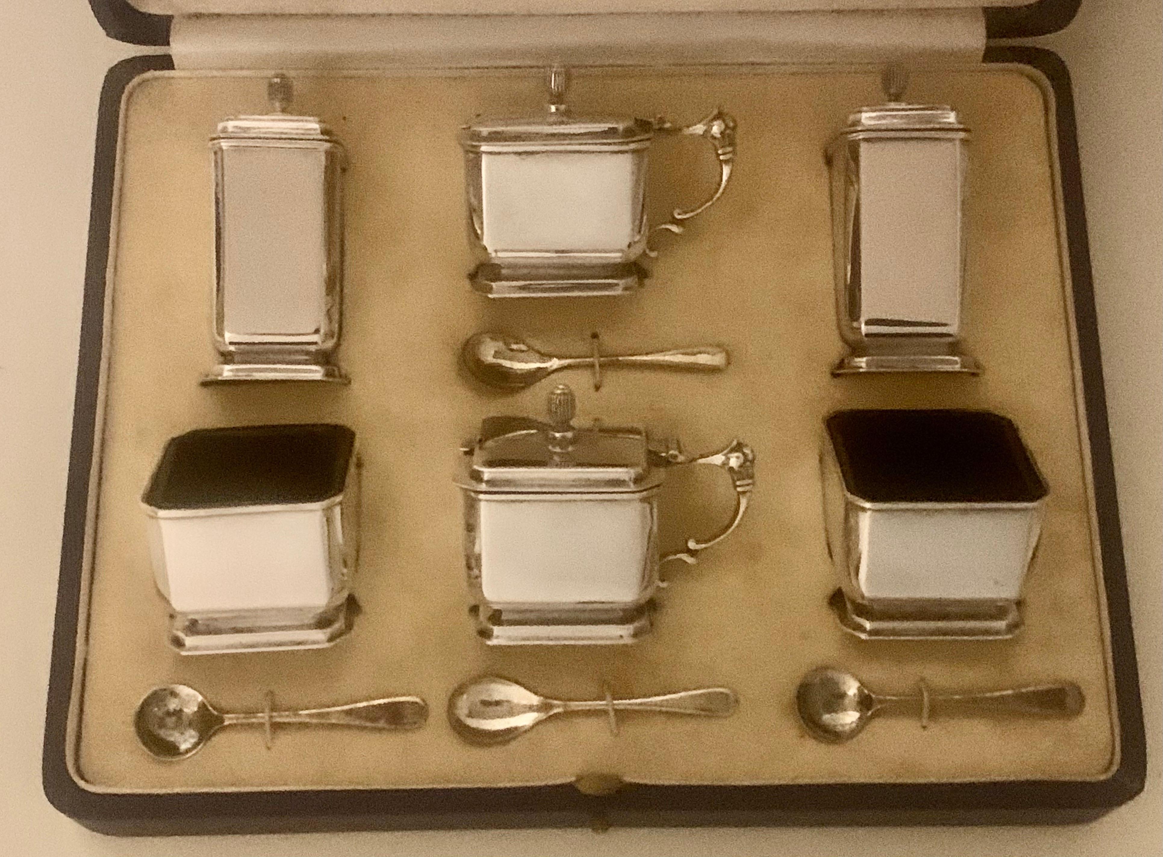 A very stylish sterling silver Art Deco six piece condiment service, having octagonal Tapered-sided bodies, with original blue-glass liners, pull-off lids on the peppers, hinged lids on the mustards, and all in their original beige velvet and cream
