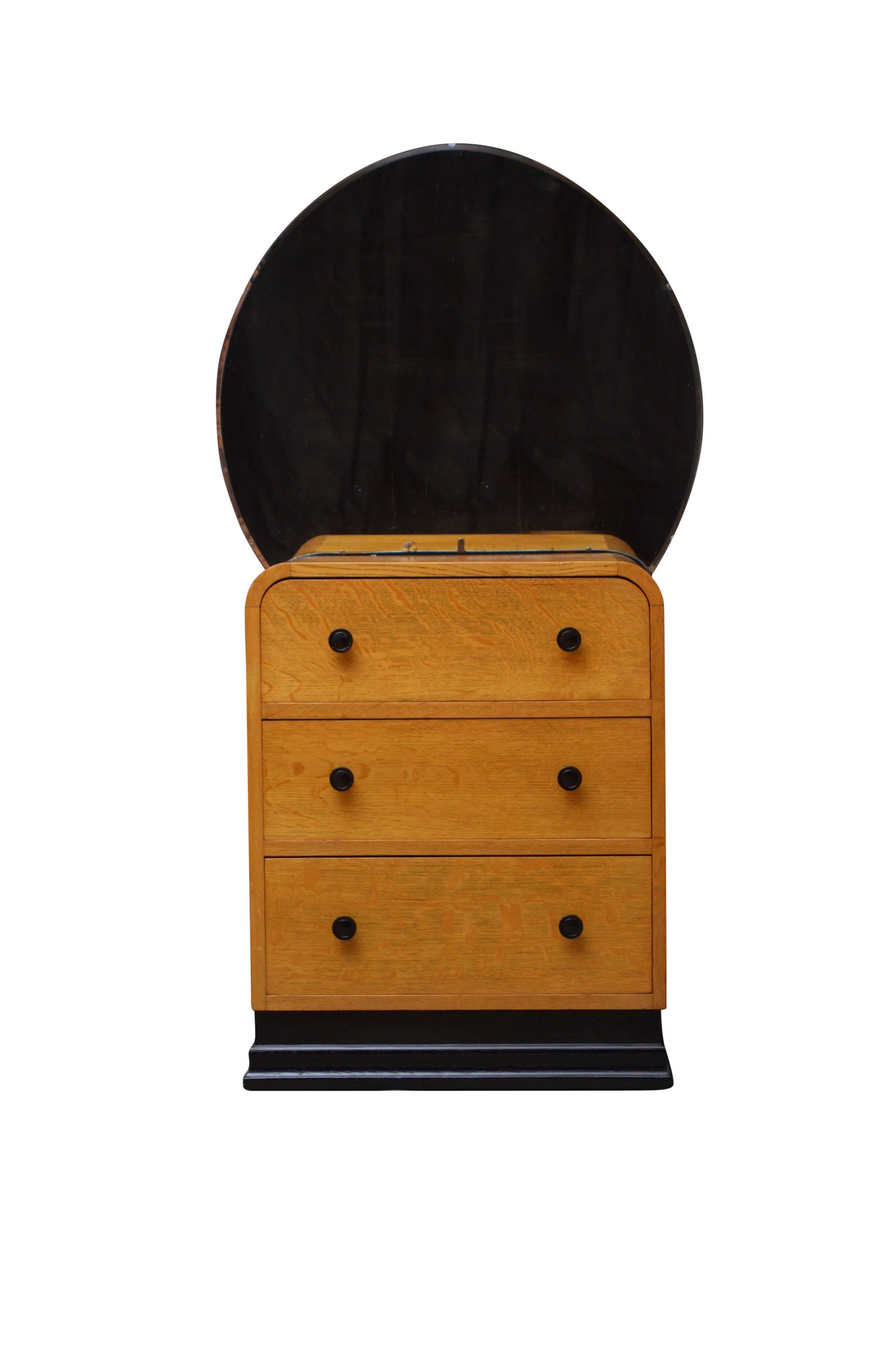 K0441, very attractive Art Deco dressing chest in oak, having original beveled mirror (small chip at the bottom) over rounded corners chest fitted with graduated drawers and ebonized handles, all standing on ebonized plinth base. This Art Deco chest