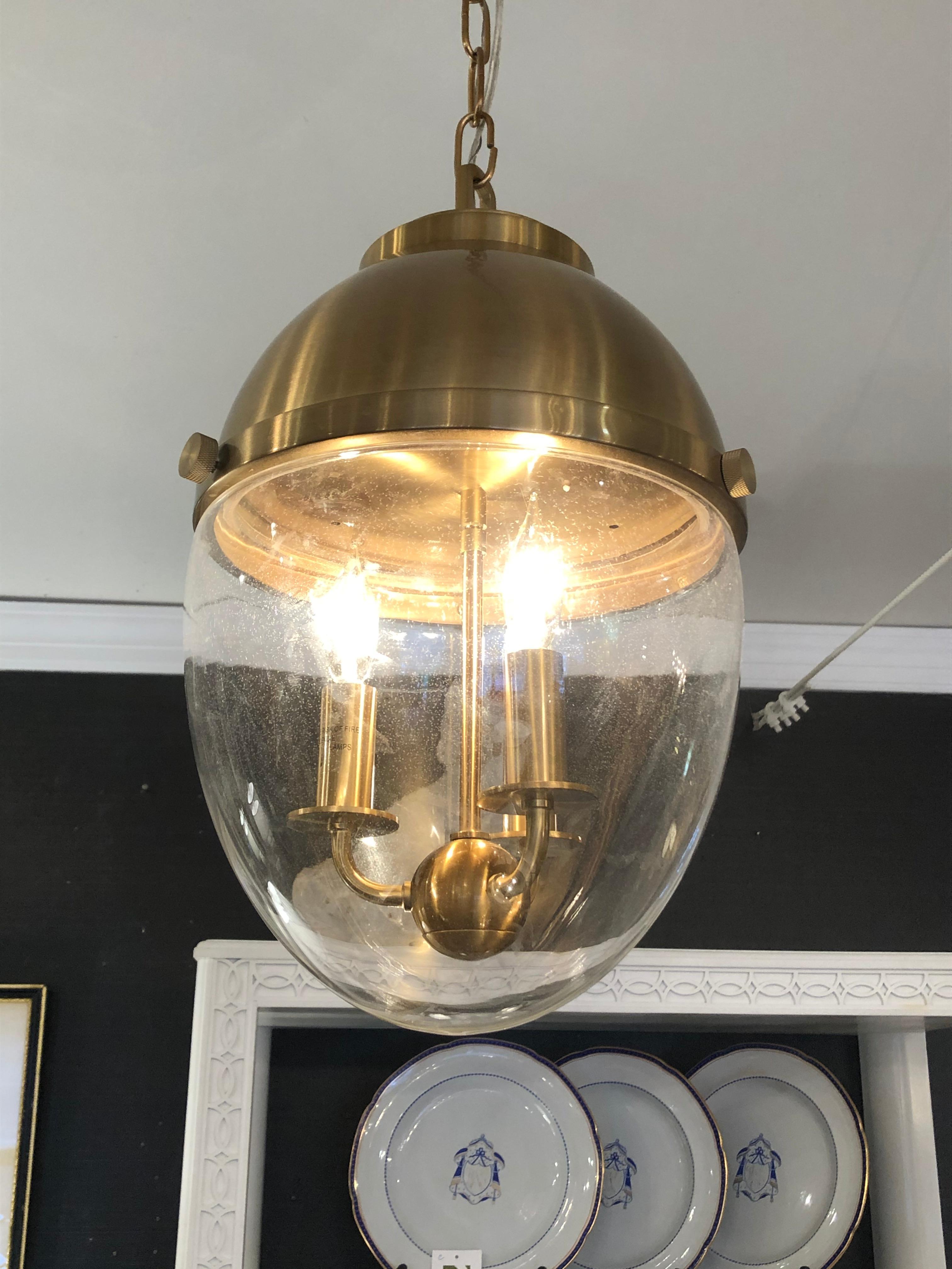Cool contemporary designed pendant chandelier having fabulous egg shape with top half brass and lower part of lantern clear glass with 3 brass candle lights inside.
3 ft of chain included.