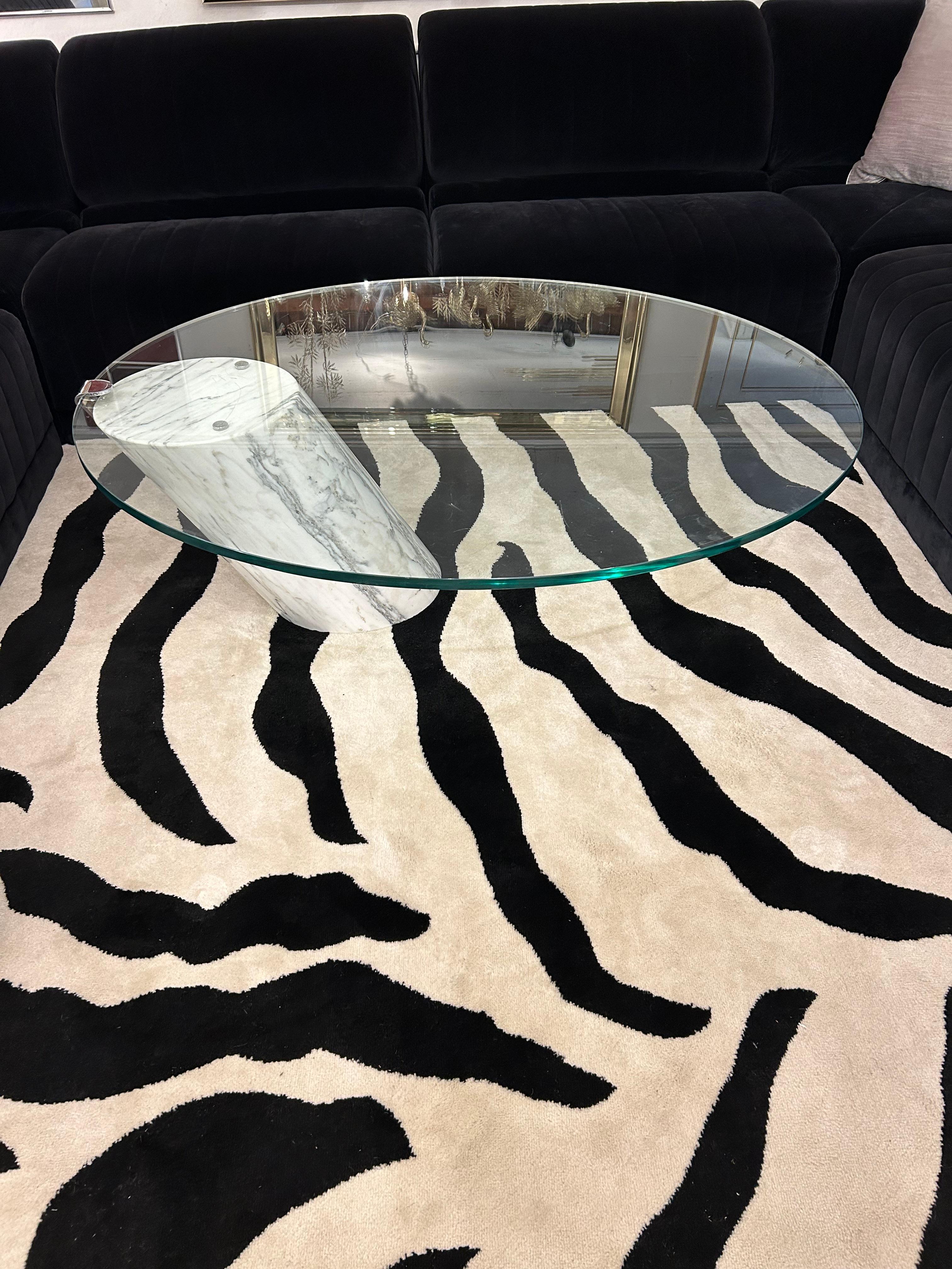 Super sleek sophisticated asymmetrical coffee table in the manner of Brueton having cantilevered heavy marble off center base and floating 3/4” thick oval glass top.