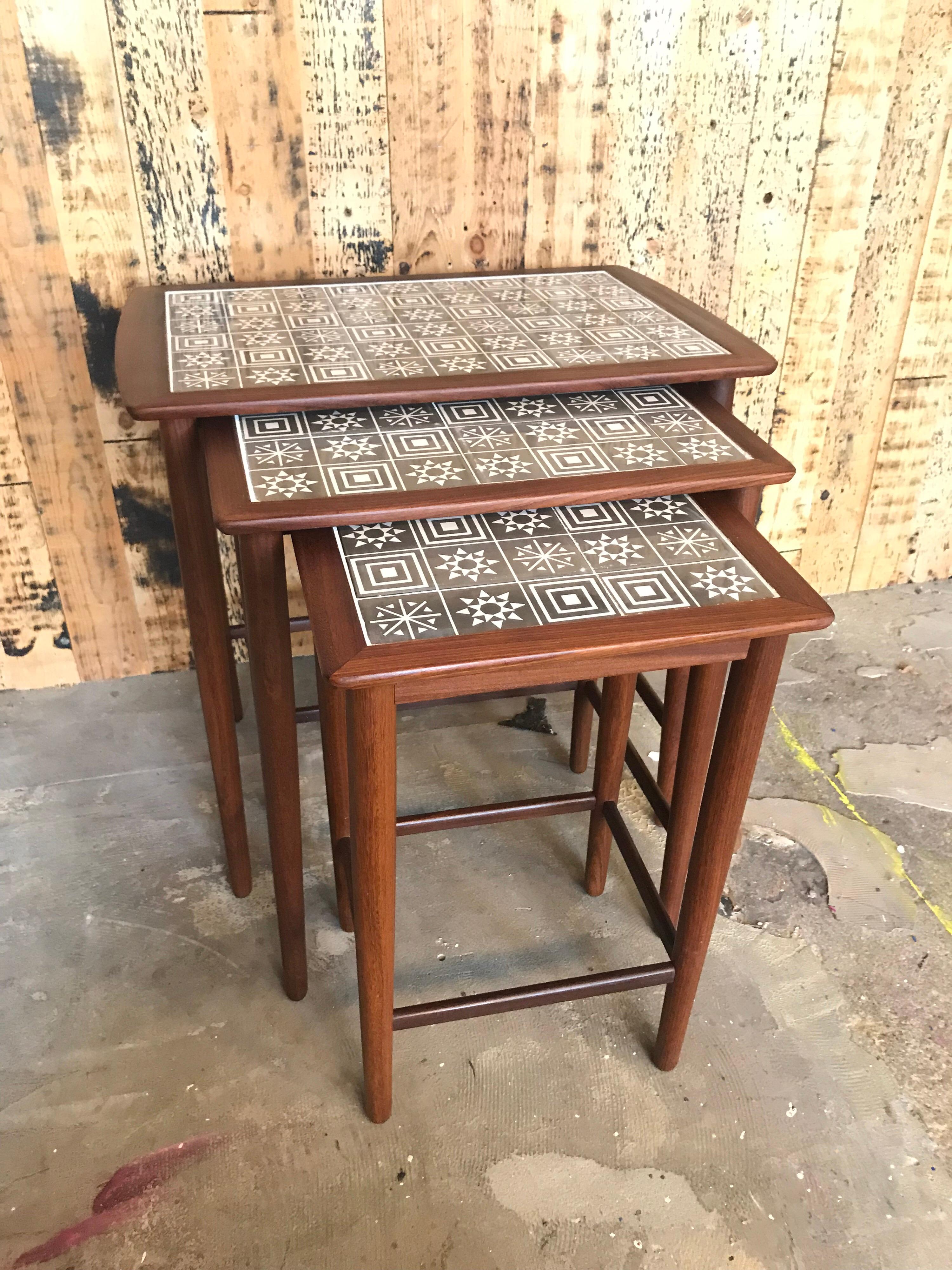 Stylish classic vintage midcentury teak nesting tables with inlaid ceramic tiles and with geometric patterns on plywood.
 