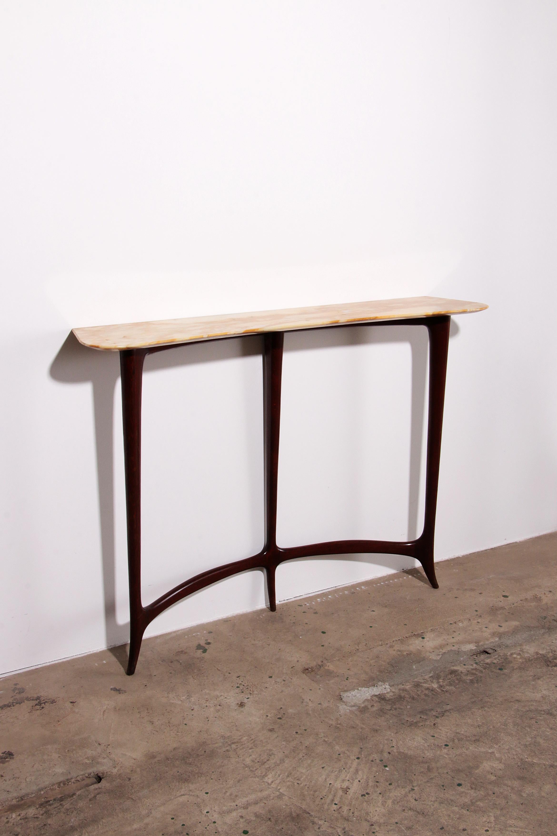 

Elevate your living space with this stylish console featuring a mustard-colored veined marble top, designed by the renowned Ezio Minotti. This elegant piece seamlessly blends modern aesthetics with timeless sophistication, making it a perfect