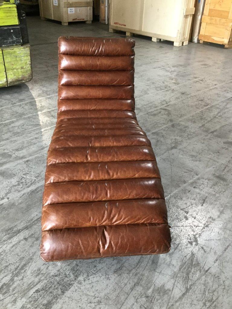 A cool and inviting leather chaise having sturdy chrome base and a rich brown tufted cushion. Buckle straps attach the cushion to the frame. Leather has a gorgeous patina and is a rich chocolately brown.