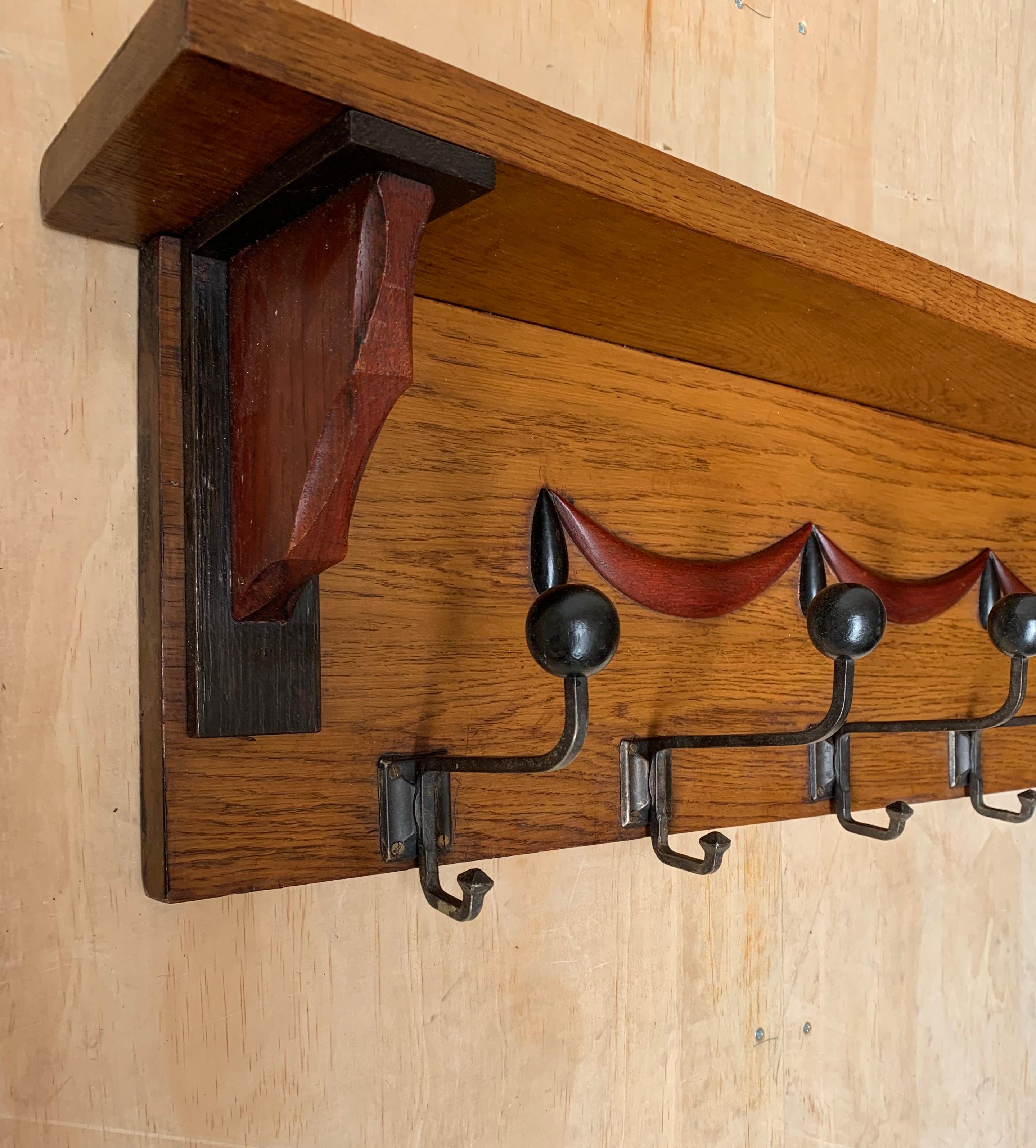 Rare and great looking wall coat-rack with a stylized theatre curtain motif.

This entry hall statement piece is made of various kinds of beautiful wood and it has a patina to die for. However, what makes this Arts and Crafts coat rack stand out