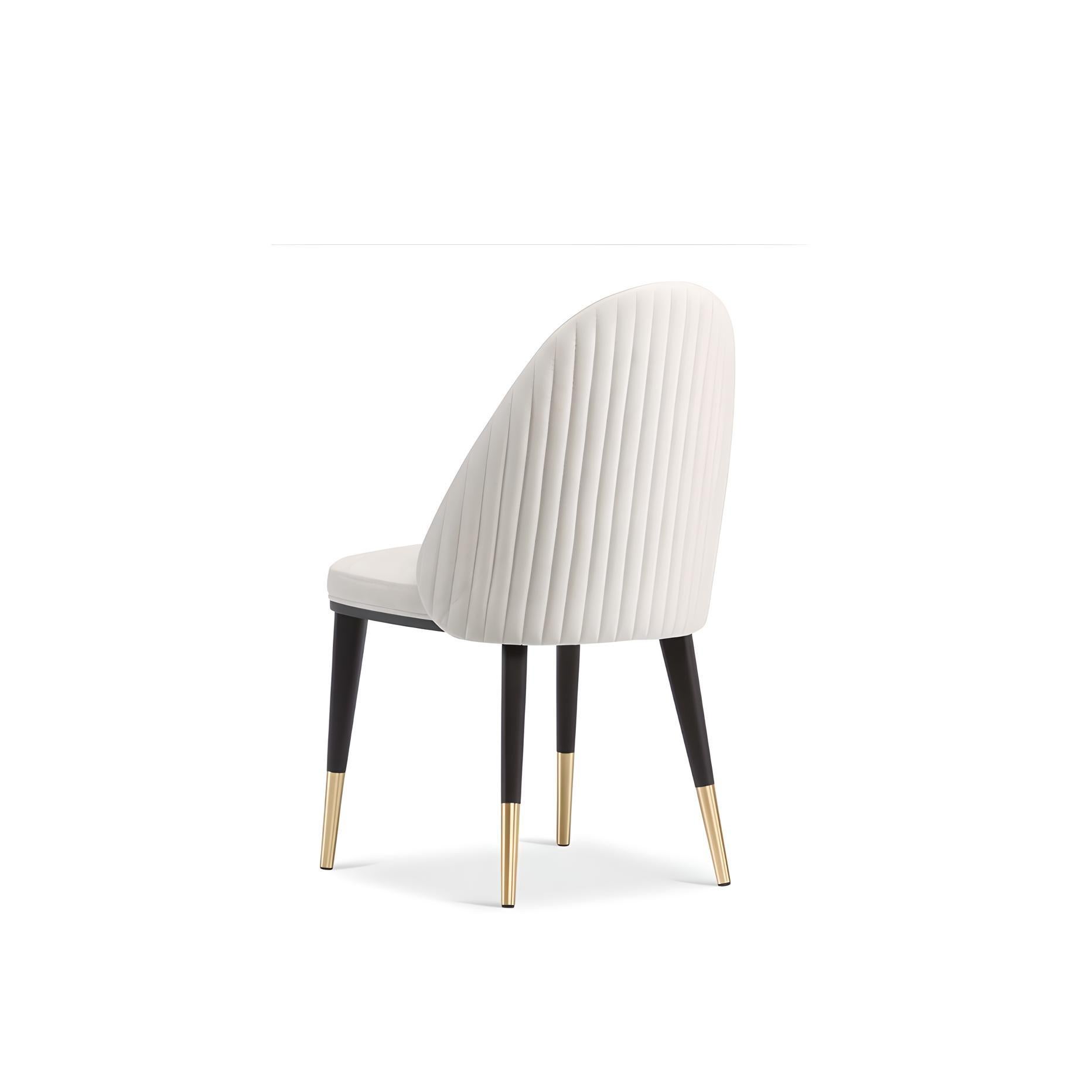 Dieser handgefertigte Stuhl wurde sorgfältig entworfen und zeichnet sich durch eine abgerundete, gepolsterte Rückenlehne mit eleganten Details im Kanalstil aus. Die Holzbeine aus schwarzer Eiche werden durch elegante Metallstützen aus gebürstetem