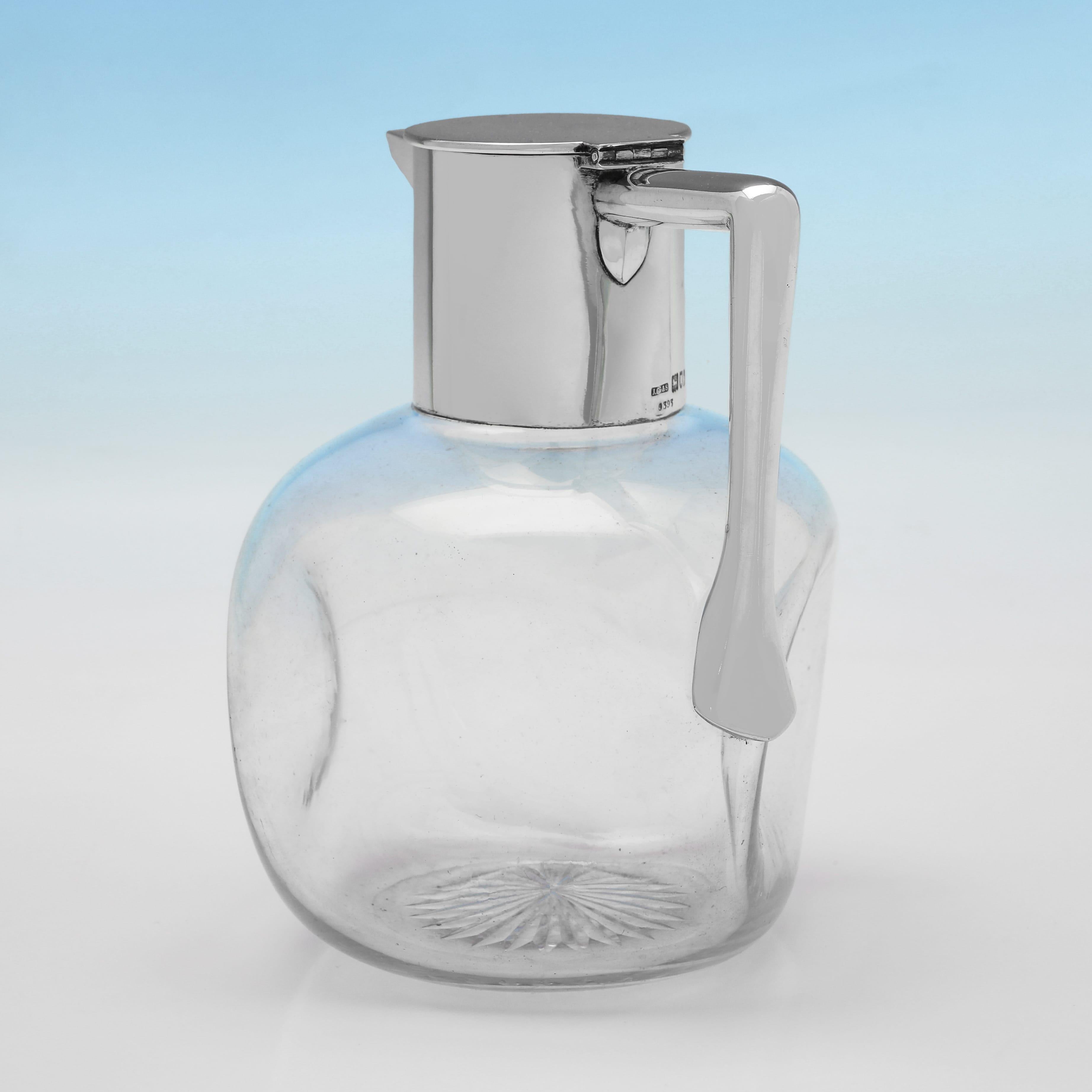 Marcada en Londres en 1903 por John Grinsell & Sons, esta elegante jarra de clarete de plata de ley eduardiana tiene el cuerpo de cristal en forma de cubo y una montura y asa de plata lisa. La jarra de clarete mide 16 cm de alto, 13 cm del asa al