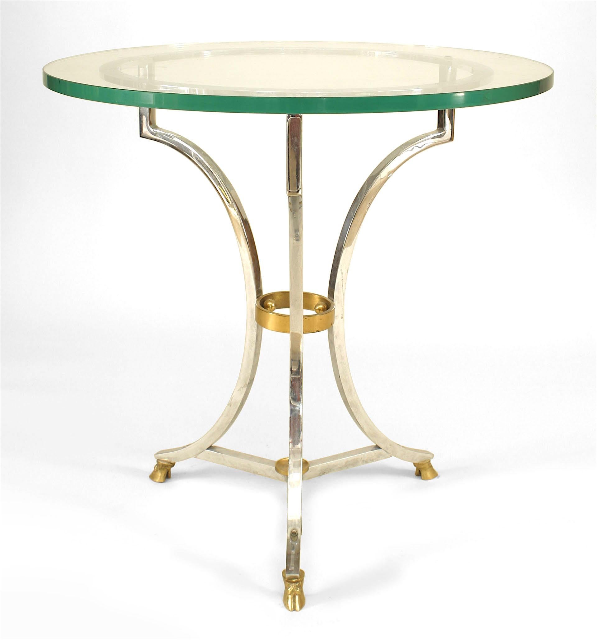 French end table with round glass top supported by a nickel plated base adorned with a brass ring and three brass hoof feet joined by a small ring stretcher.