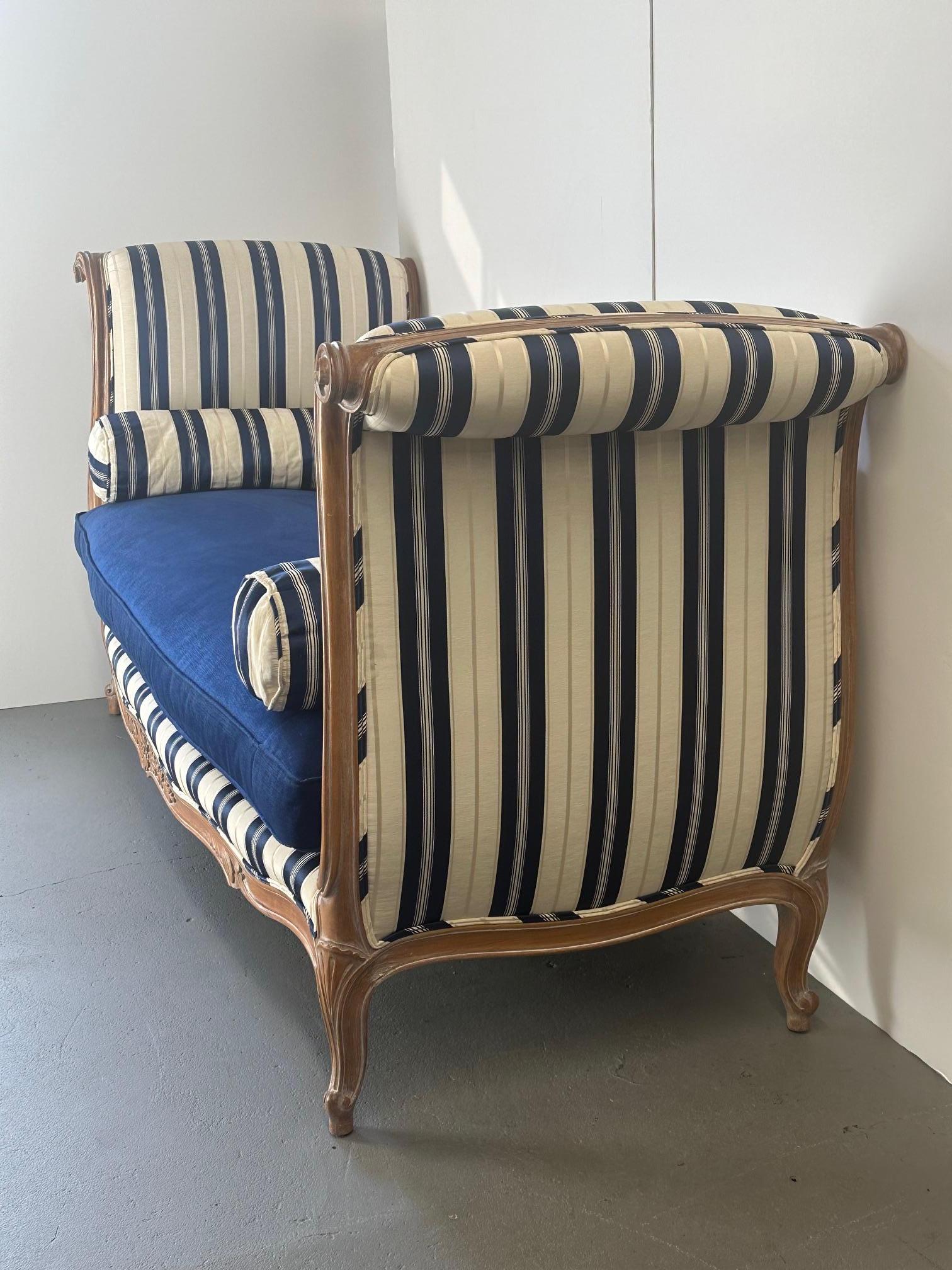 Magnifique causeuse de style français en bois sculpté et cérusé, dont le corps est recouvert d'une élégante tapisserie à rayures bleues et blanches en soie et coton.  Le site  Le coussin d'assise bleu marine est un duvet enveloppé de Dacron.
Le