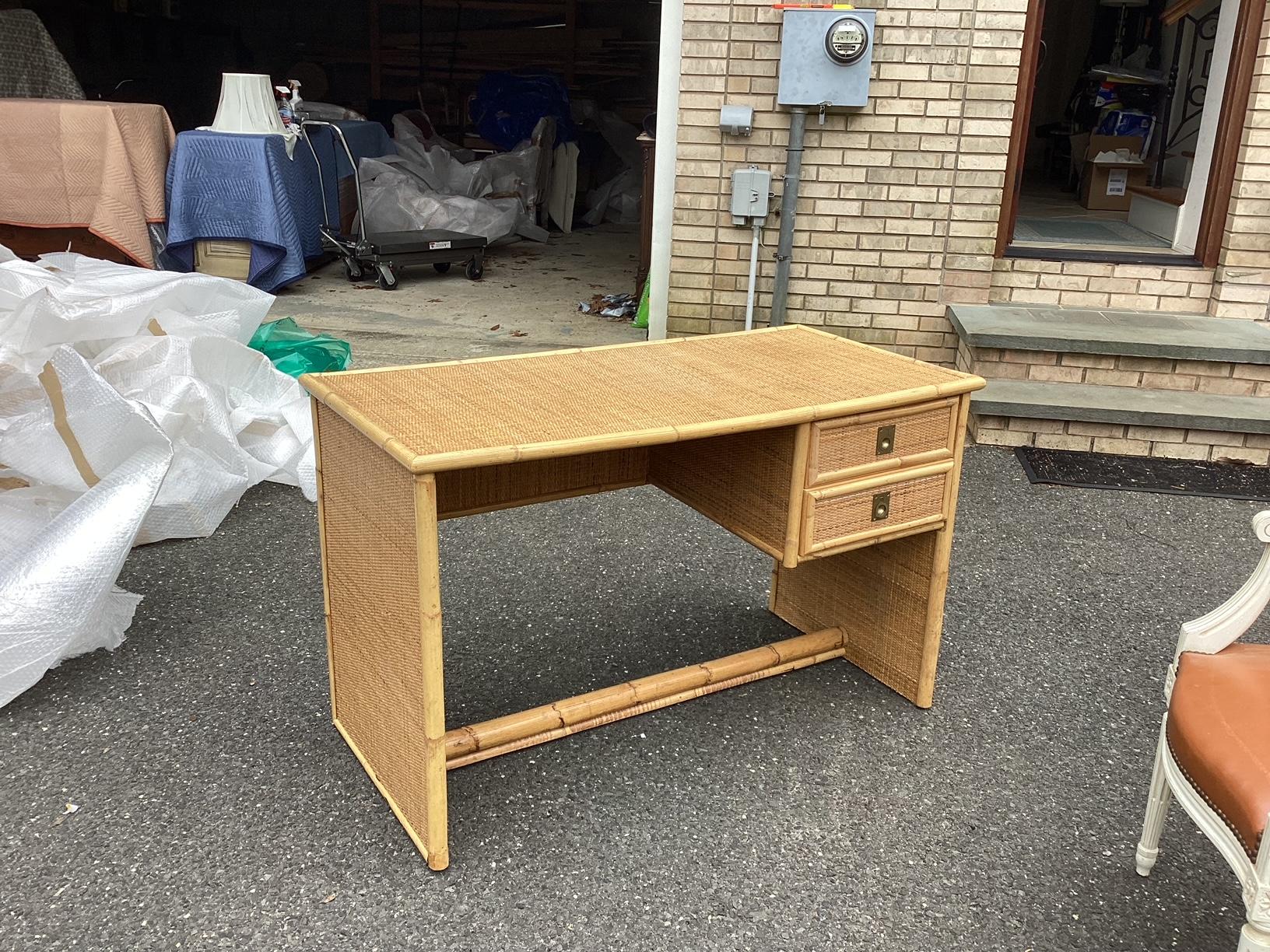 This is a classic French rattan writing desk having clean, modern lines and large workspace. The sides are full rattan panels. There are bamboo accents around the drawers and a full bamboo bar across the bottom of the desk. TThe color is natural and