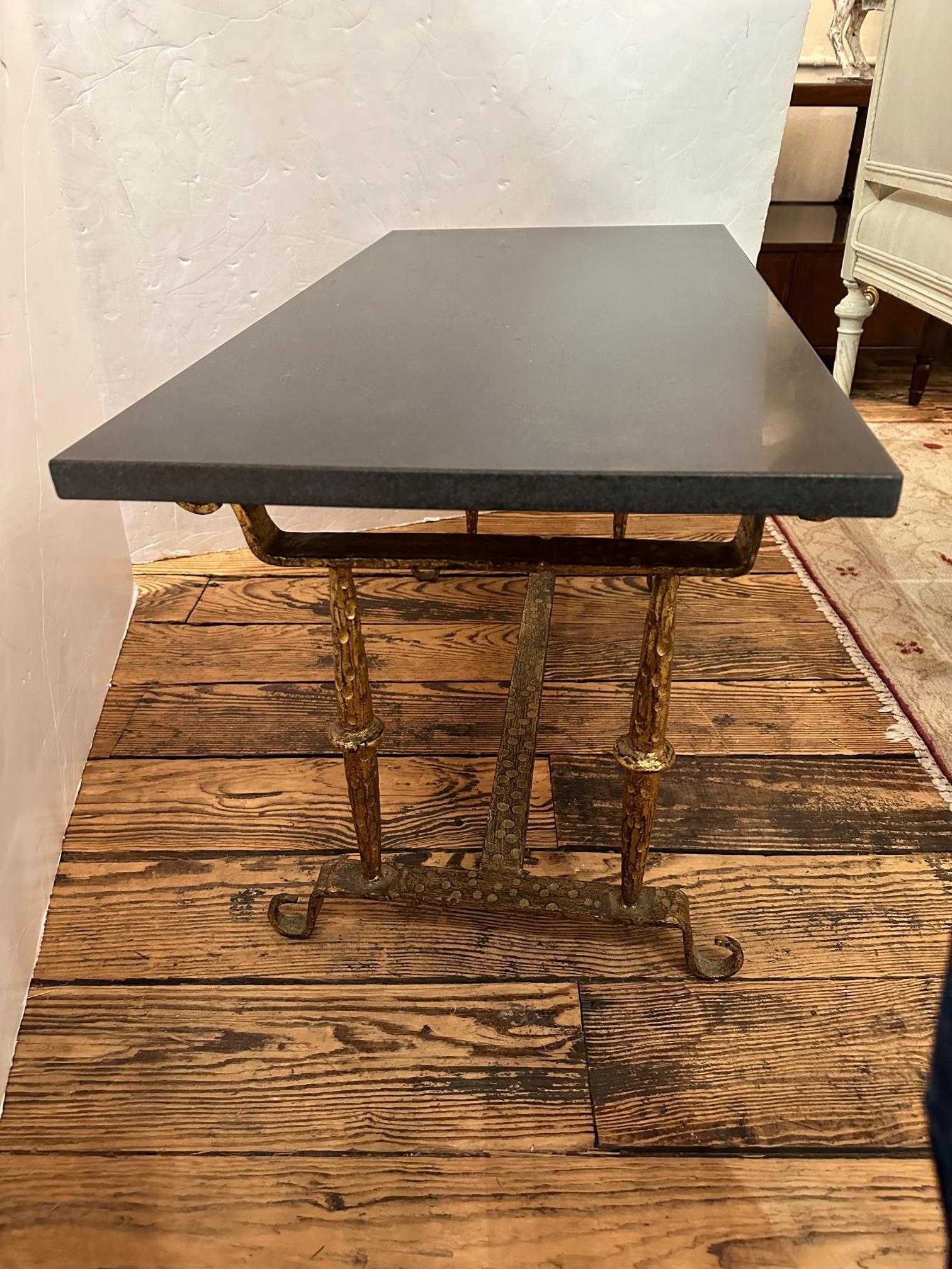 Elegant small hammered gilt iron cocktail table with black marble rectangular top.