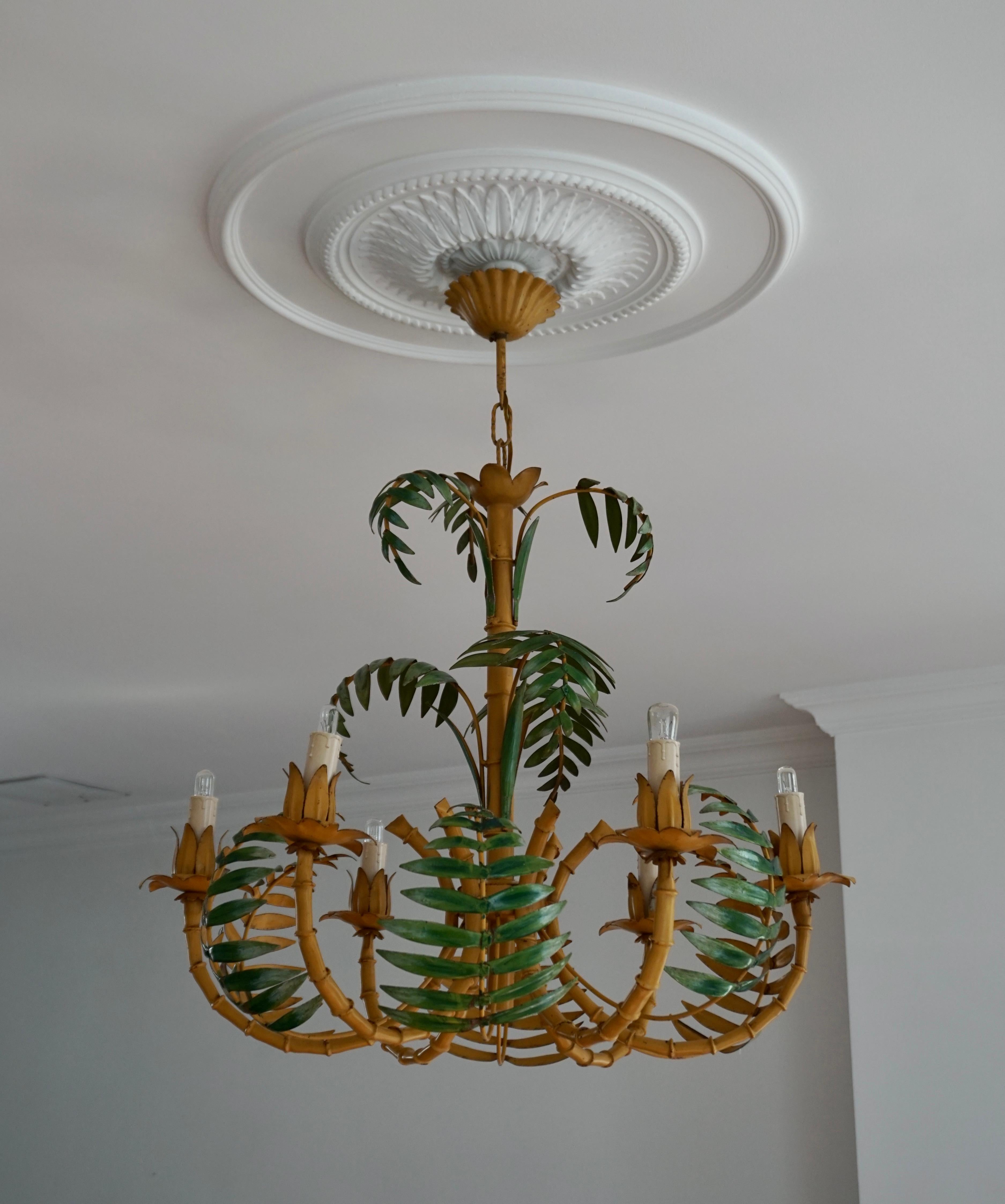 Super chic pale yellow faux bamboo Hollywood Regency chandelier with green leaves, perfect for a hallway or foyer, having 6 arms and wonderful construction of tole, iron and faux bamboo. We love the color. Original canopy and wiring.

Measures: